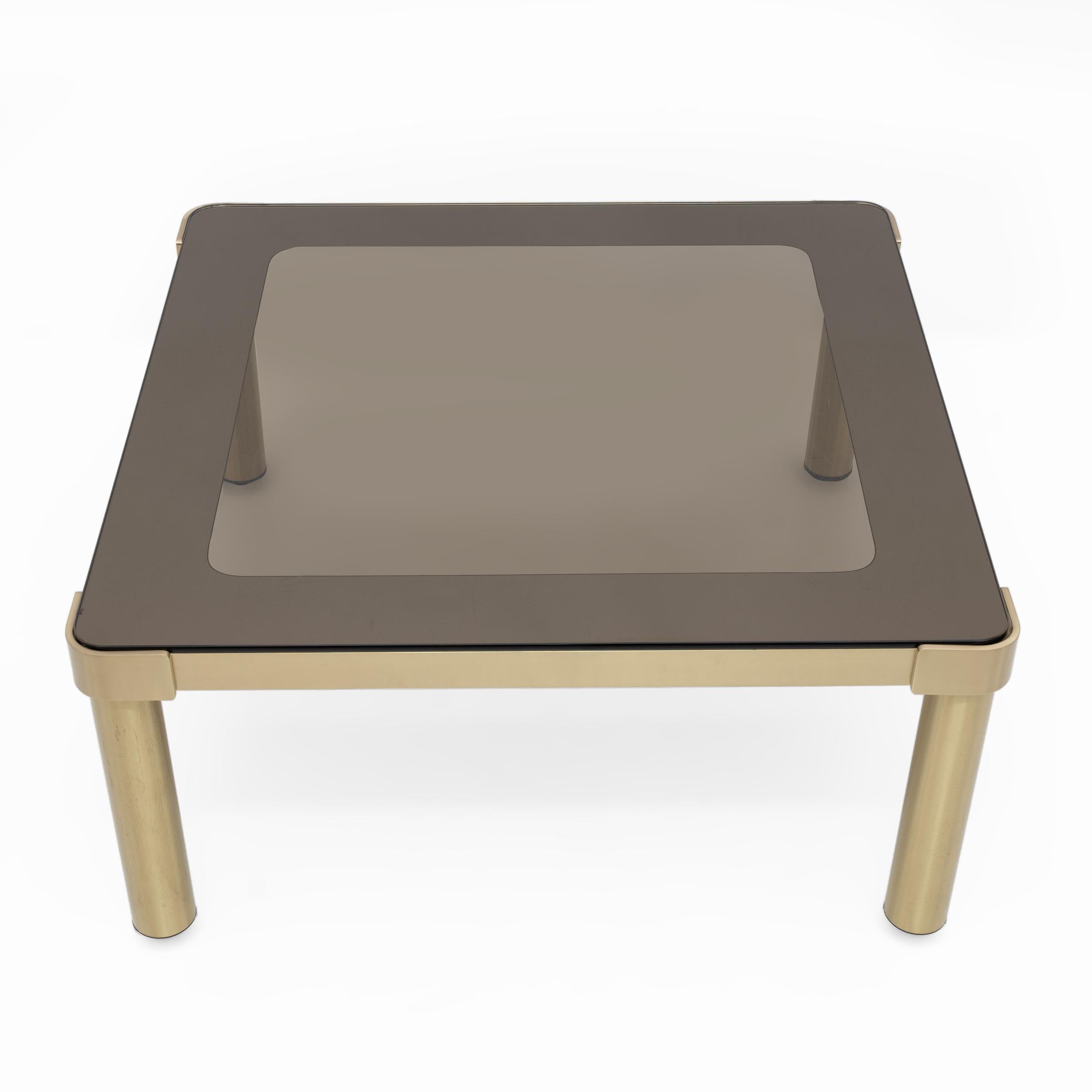 Table basse en laiton moderne du milieu du siècle avec plateau en verre fumé par Luciano Frigerio, années 1970. Cette table basse unique a été conçue par le designer italien Luciano Frigerio dans les années 1970. Le cadre est en laiton épais, avec