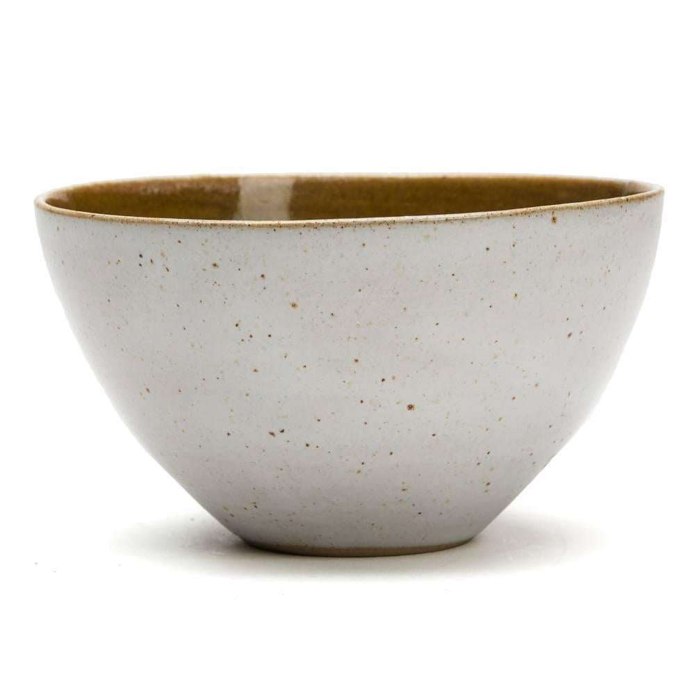 A stunning vintage British studio pottery bowl by Lucie Rie and Hans Coper, finely thrown the outer body decorated in oatmeal glaze with a dark mustard glaze to the inside bowl. The rounded bowl is slightly 'squeezed' in shape and stands on a narrow