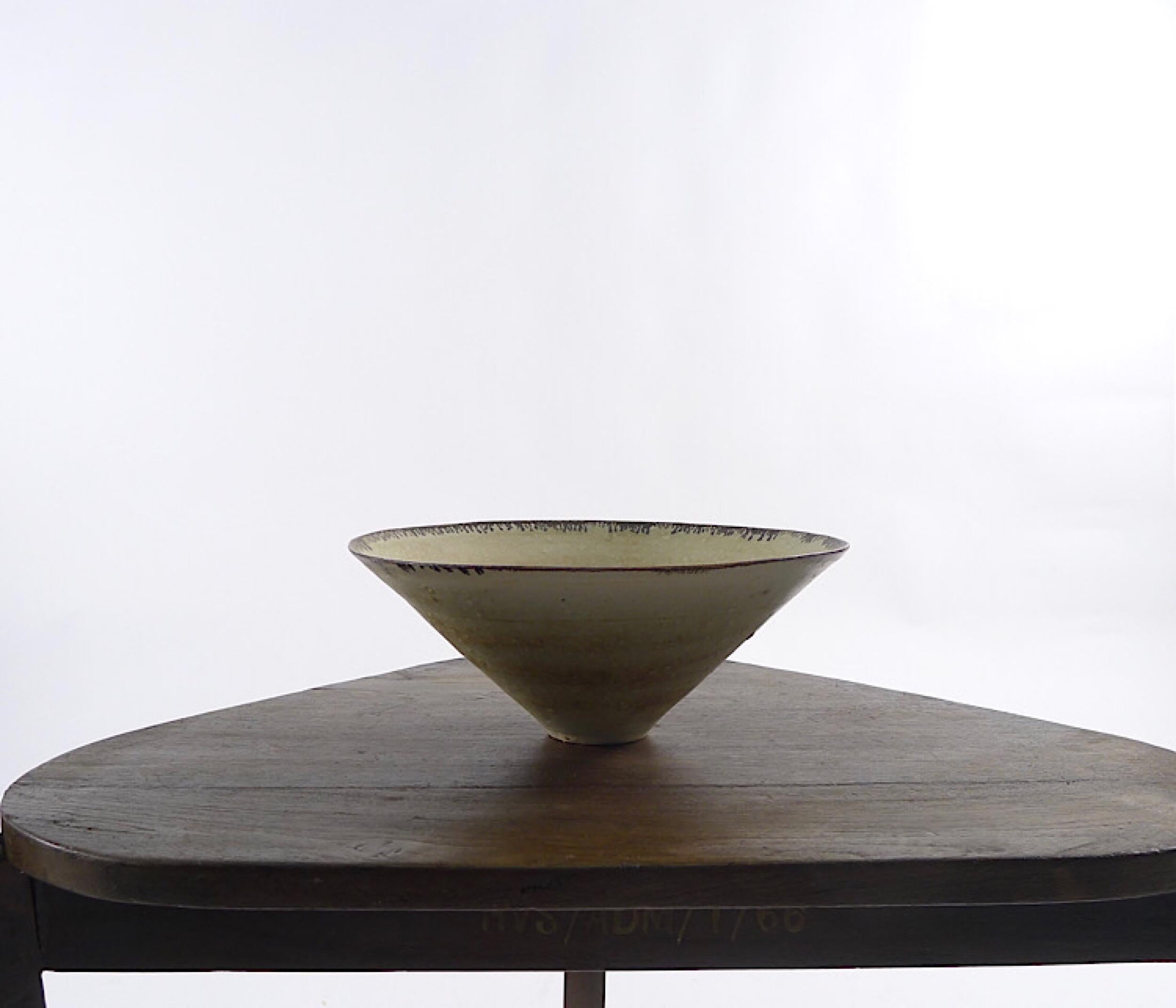 Dame Lucie Rie DBE (British/Austrian 1902-1995), porcelain bowl of flaring conical form, pitted mint blue and fawn glaze with running manganese band to rim, impressed seal mark.

Condition excellent. Measure: 24cm diameter.