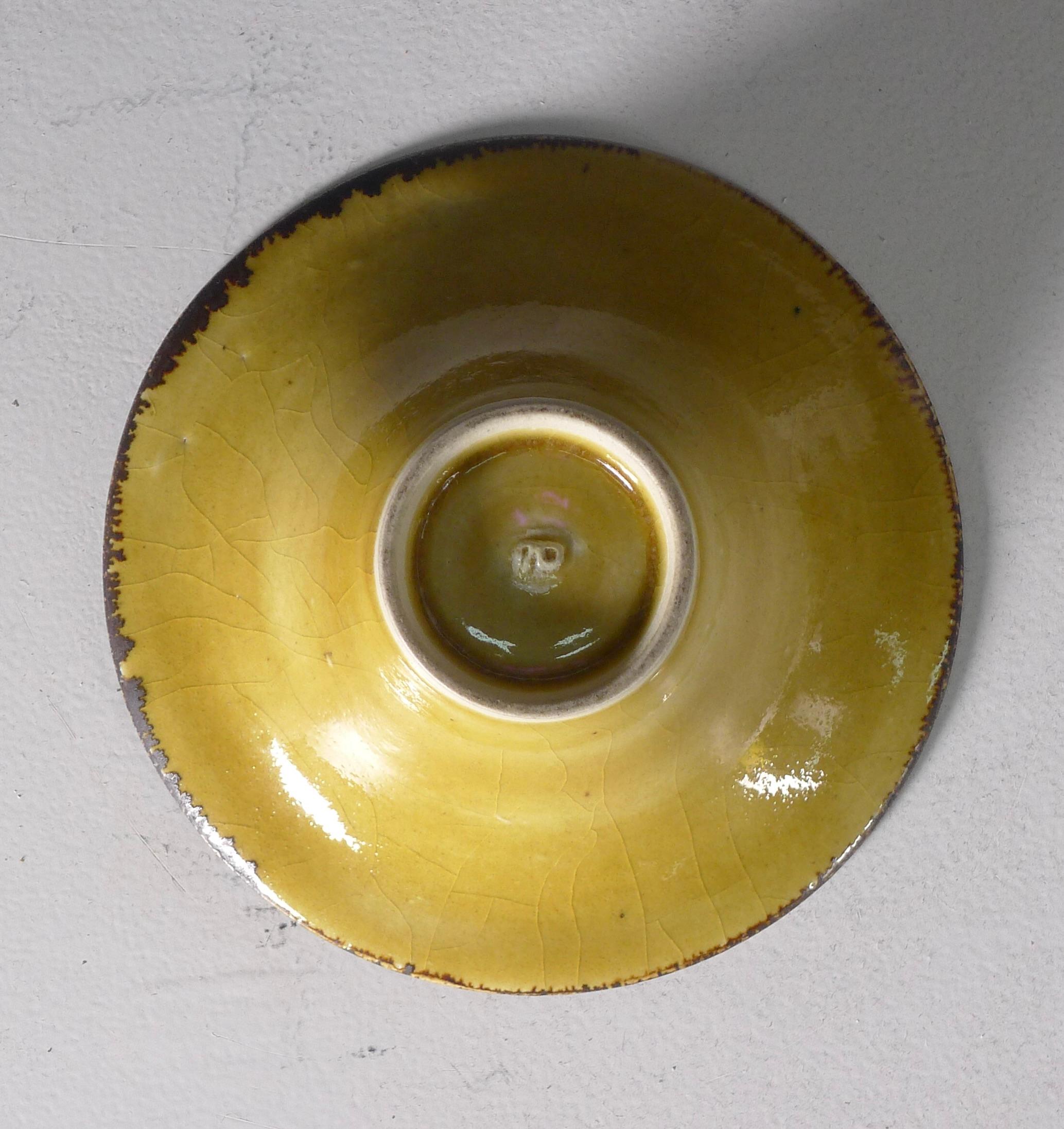 Lucie Rie (British/Austrian 1902-1995), a porcelain bowl of flaring form, uranium yellow glaze with craquelure and running manganese band to rim, impressed seal mark, 14.7cm diameter, 5.9cm high

This bowl, with its slightly irregular shape,