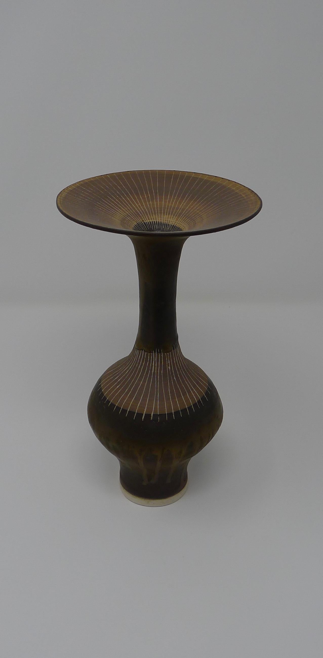 Lucie Rie, tall porcelain bottle form vase with flaring rim, bronzed sgrafitto lines through light brown slip. Signed with impressed mark to underside.

Excellent Provenance from important private collection. 
Perfect condition.