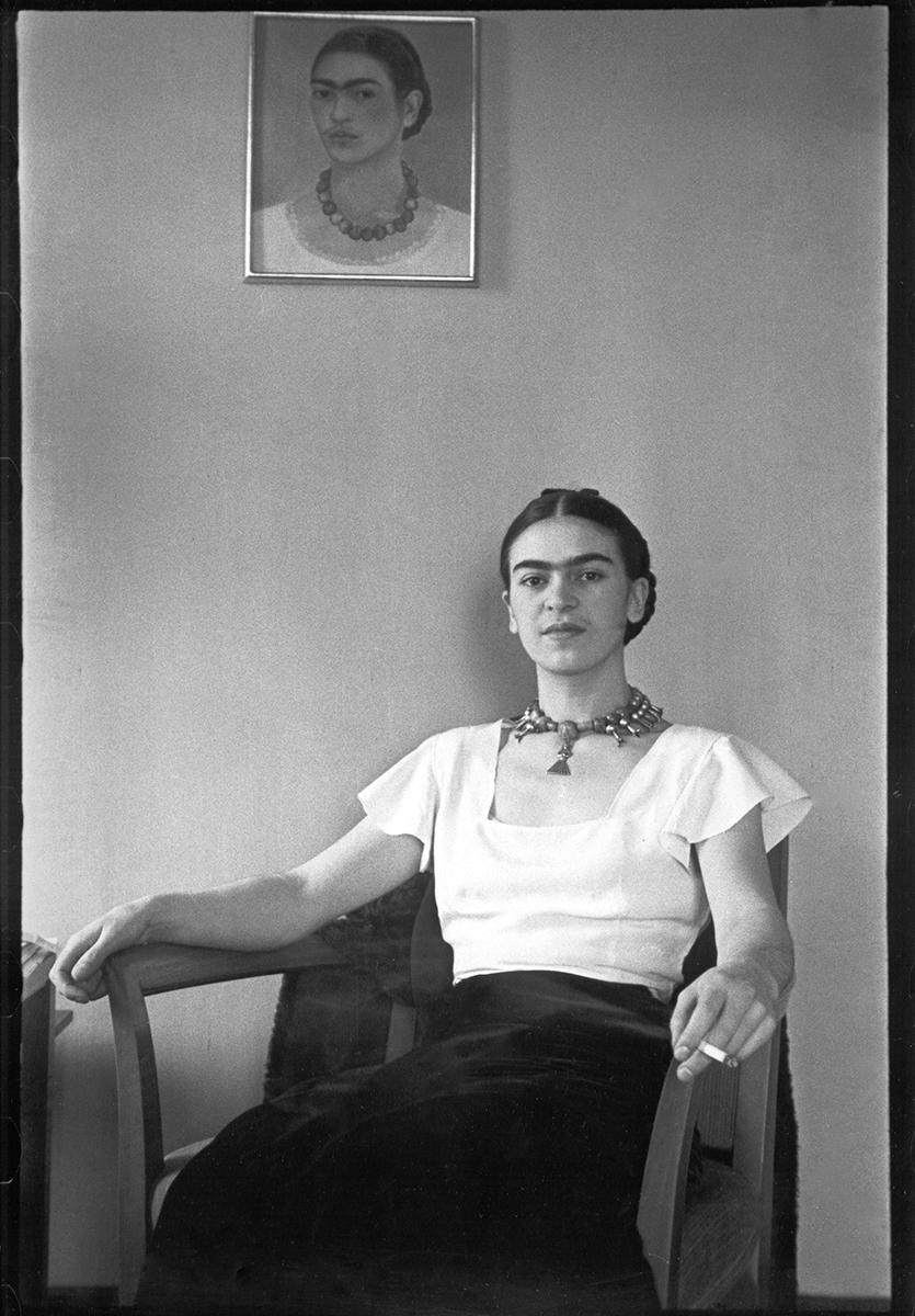 Frida at the Barbizon Plaza Hotel von Lucienne Bloch ist ein Schwarz-Weiß-Porträt der mexikanischen surrealistischen Malerin Frida Kahlo, die auf einem Stuhl unter ihrem Selbstporträt an der Wand sitzt. 

Bildgröße: 11,63 x 8 Zoll.
Größe des