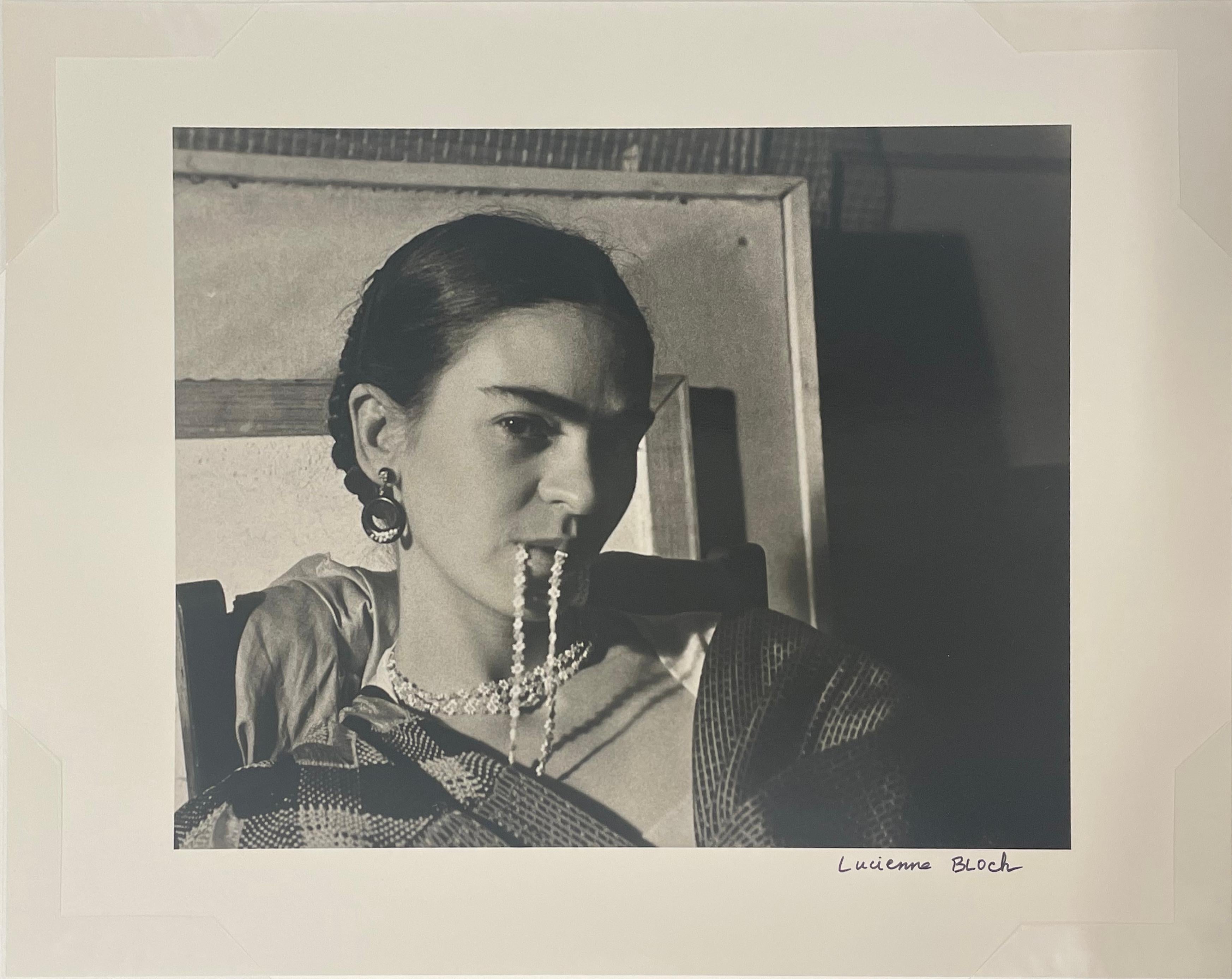 Frida Biting Her Necklace by Lucienne Bloch is a 8 1/4 x 10 1/4 inch silver gelatin print. This photograph is mounted on a 16 x 20 inch mount board with a window mat. It is signed on print recto by artist in pen and has a signature label on mount