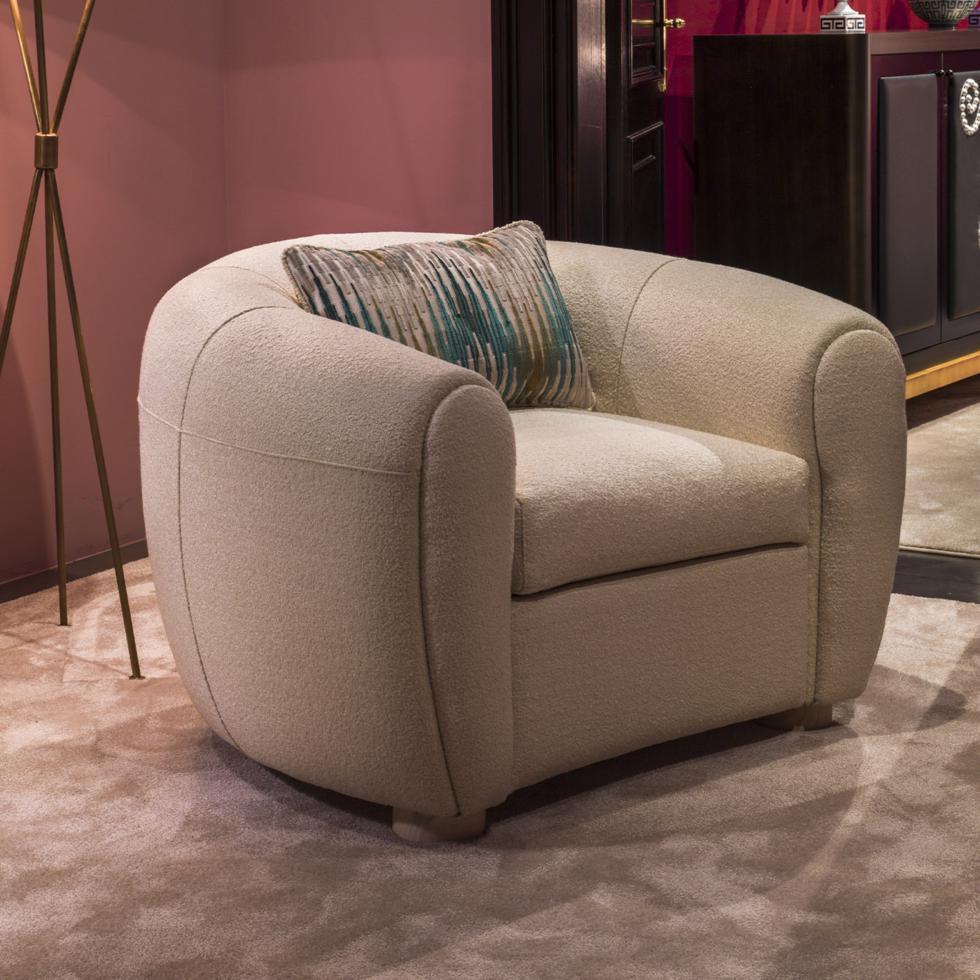 A spacious seat exuding luxurious comfort, this refined Lucille armchair flaunts a curved barrel-shaped silhouette for ultimate elegance and relaxation in a modern or classic living interior. Featuring a plushly padded frame and seat cushion,