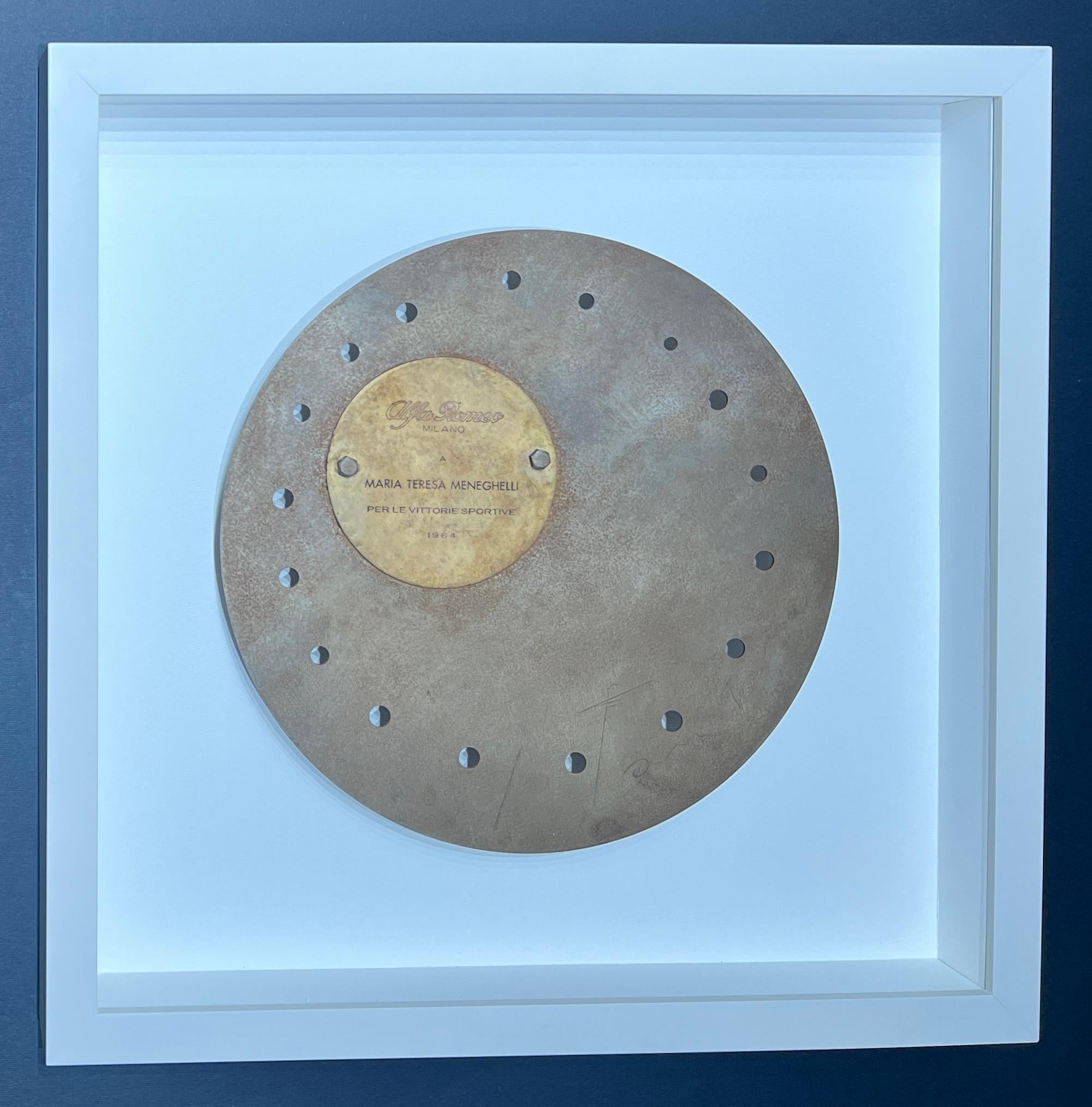 Scultura in metallo di Lucio Fontana commissionata nel 1964 dall'Alfa Romeo, un disco d'acciaio lavorato e forato, con un disco più piccolo apposto con l'incisione "Alfa Romeo Milano a Maria Teresa Meneghelli per le vittorie sportive 1964", con