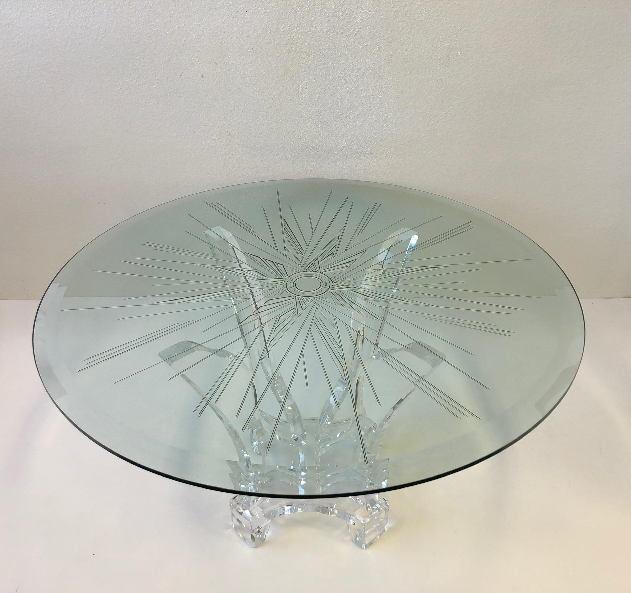 A glamorous thick Lucite table base with a custom carved starburst design glass top. The table was designed by Lion in Frost in the 1980s. The glass top is 3/4” thick with a double beveled. The table is in excellent condition with some minor wear