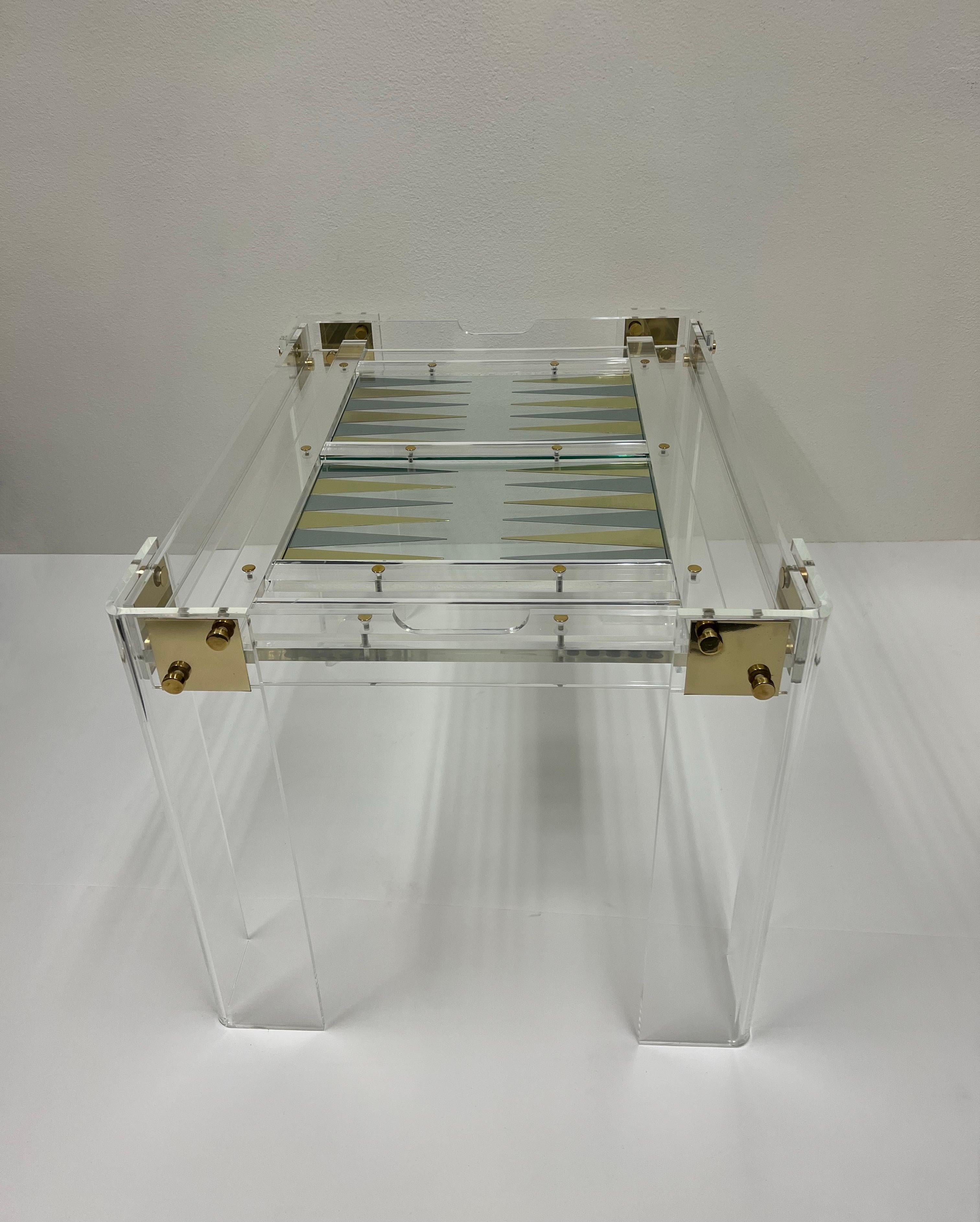 Glamorous 1970’s lucite and brass with bakelite pieces backgammon table design by American renowned designer Charles Hollis Jones. 
Newly professionally polished, shows minor wear consistent with age, minor crazing on one of the legs. 
Measurements: