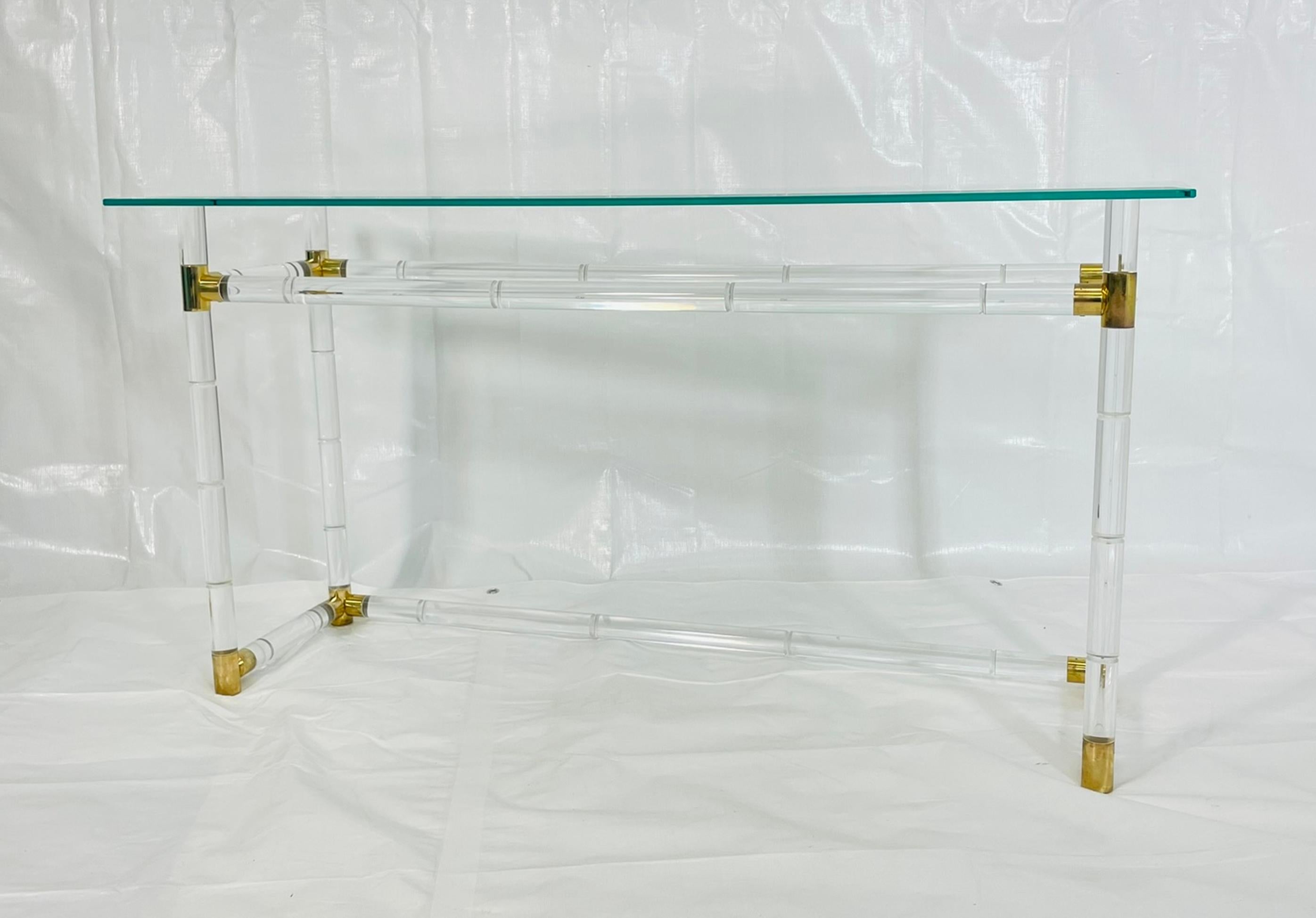 Elegant Lucite and brass console table with glass top, designed and manufactured in the United States by Charles Hollis Jones in the late 1960s. The table exemplifies Jones’s signature fusion of modern glamour and technical innovation, featuring a