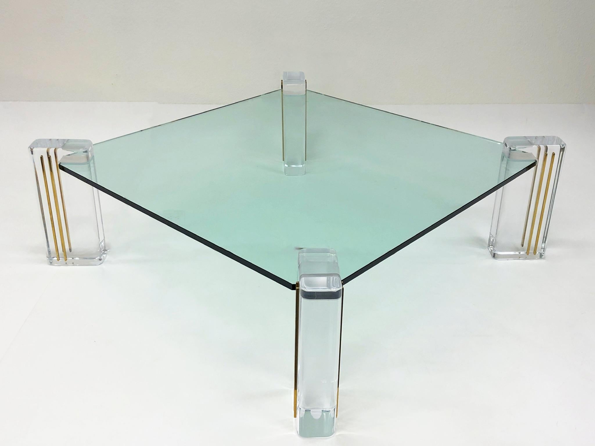 A glamorous Lucite and brass inlay with glass top Cocktail table designed by Karl Springer in the 1980s. The table has new 3/4” thick glass top and the acrylic legs have been newly professionally polished. 

Overall dimensions: 53” wide 53” deep