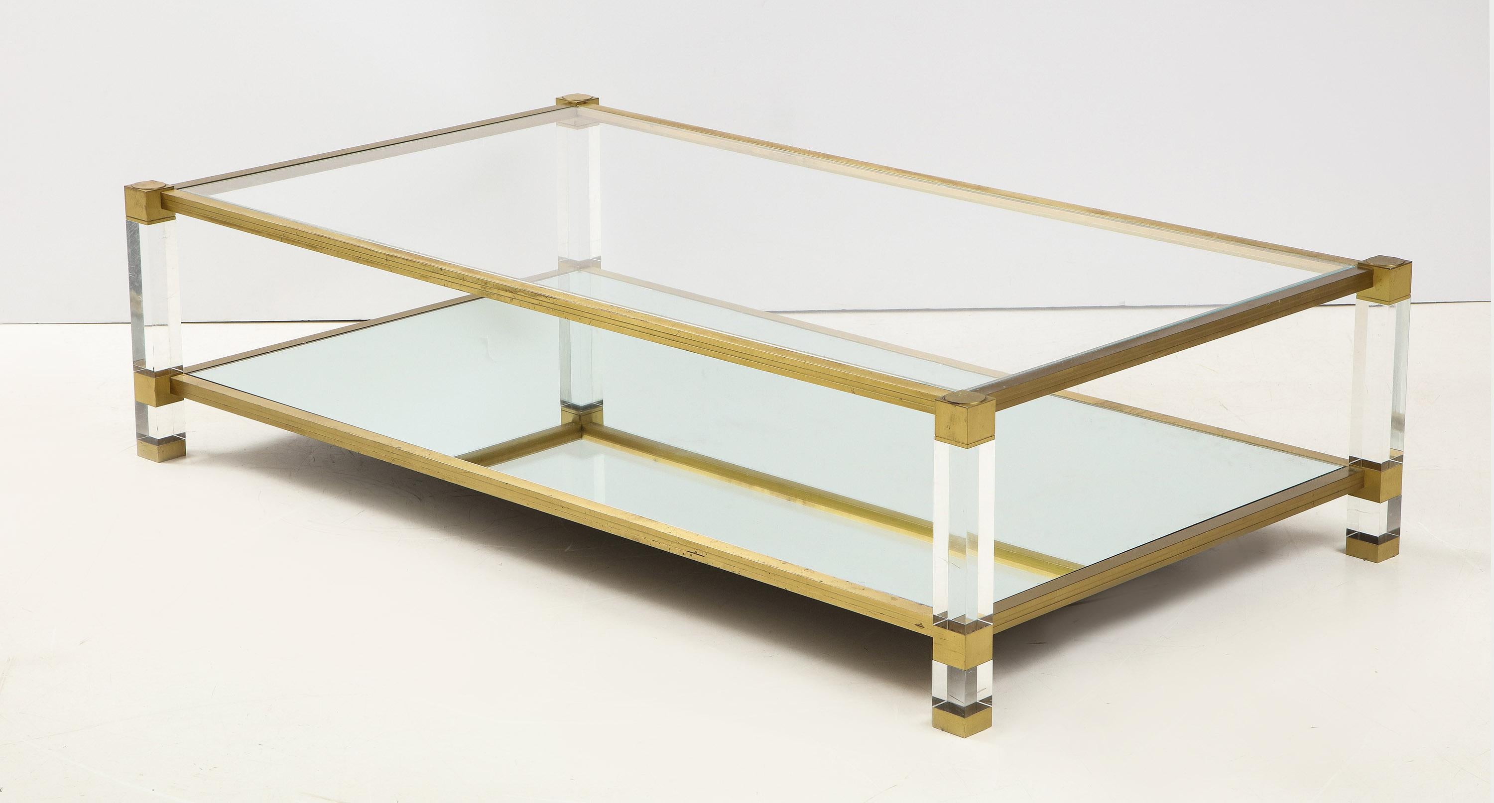 A large French Mid-Century Modern, two tier cocktail table in Lucite and brass by Pierre Vandel. The rectangular form with top section inset with glass and the lower inset with mirror.