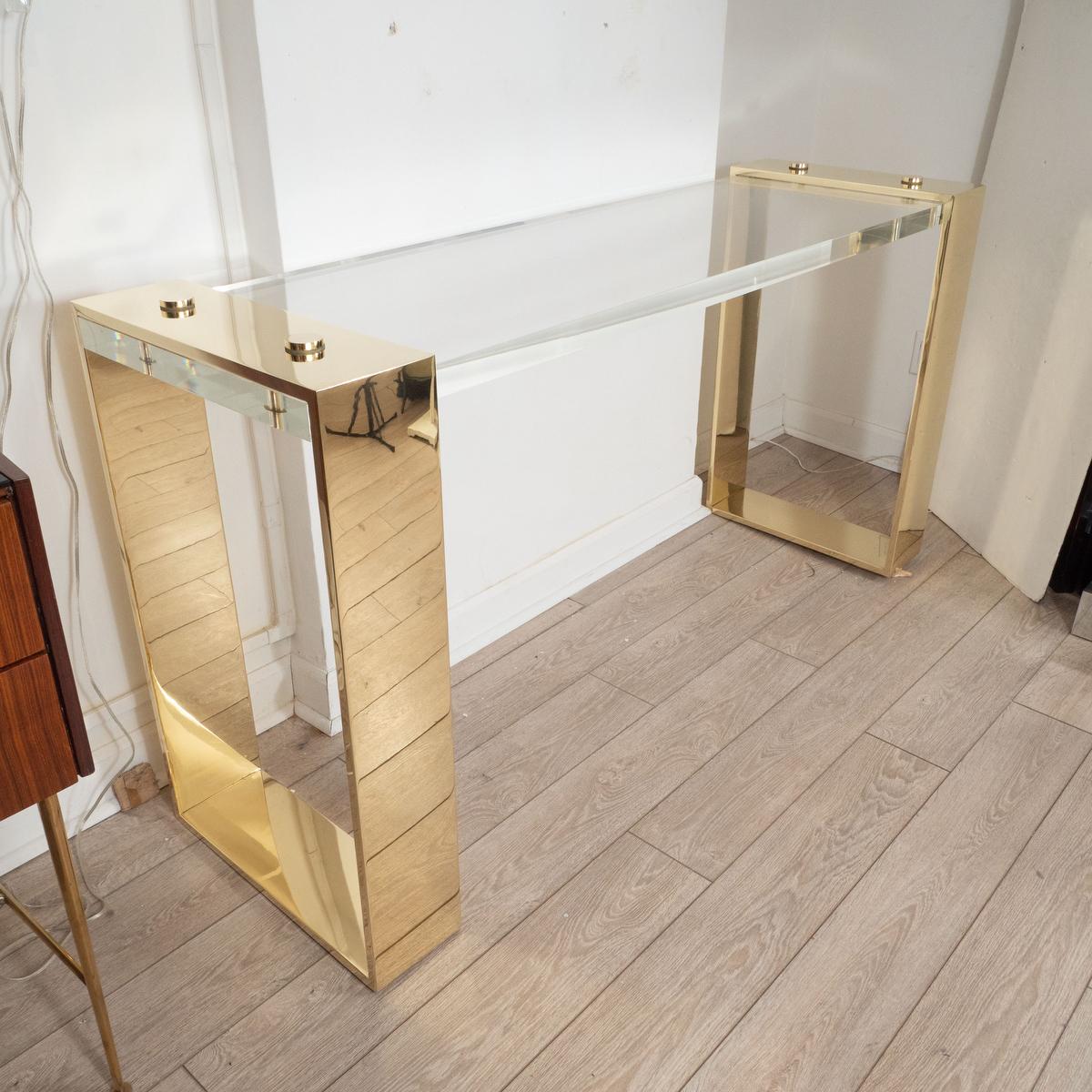 Console table composed of Lucite slab with open design brass legs.