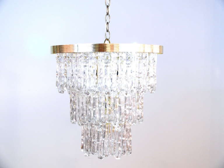 Beautiful three-tiered Lucite chandelier suspended from a brass frame reminiscent of Venini crystal chandeliers. Wired and ready to use. Measurement is without brass chain.