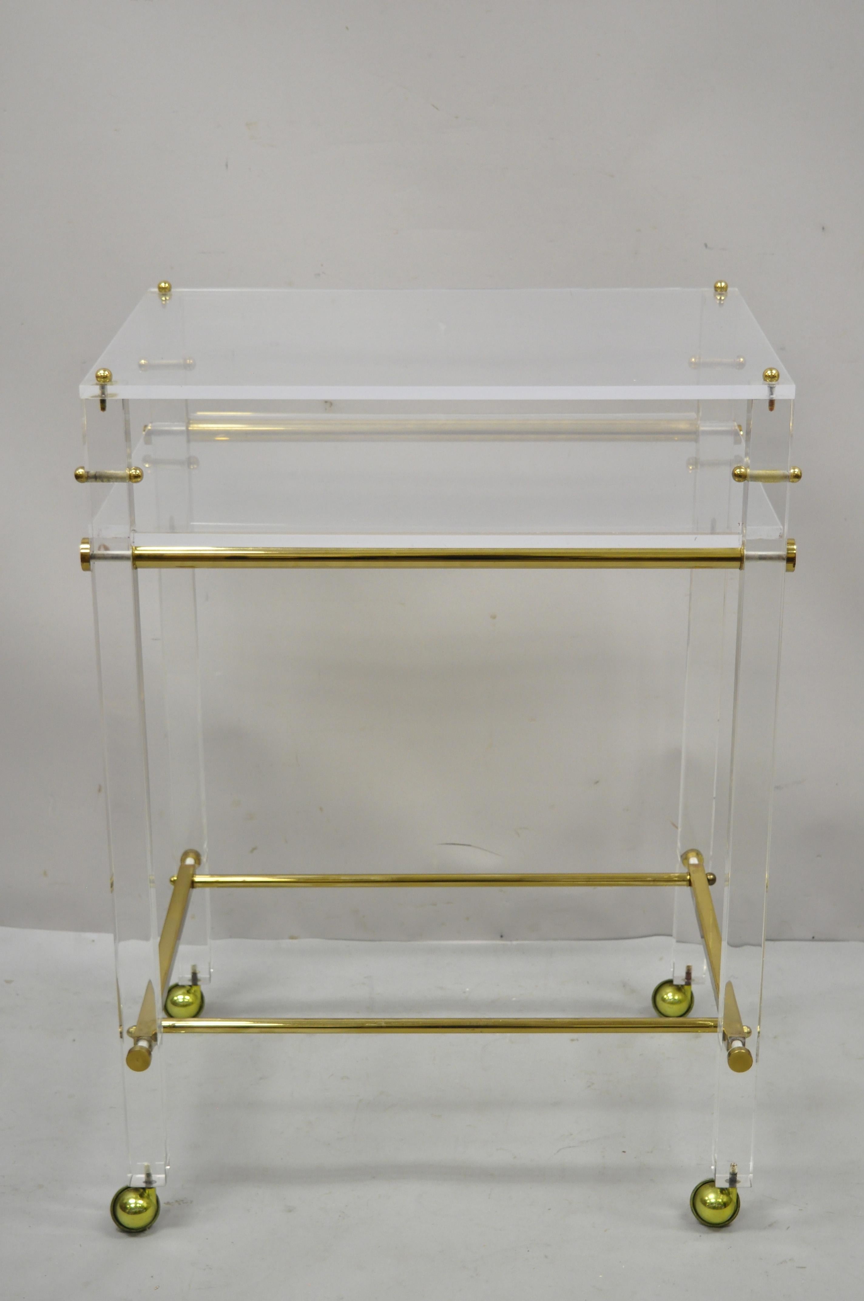Lucite and brass mid century modern rolling bar cart trolley tea table stand. Item features brass stretcher base, rolling casters, lucite upper level with shelf, clean modernist lines, great style and form. Circa mid to late 20th