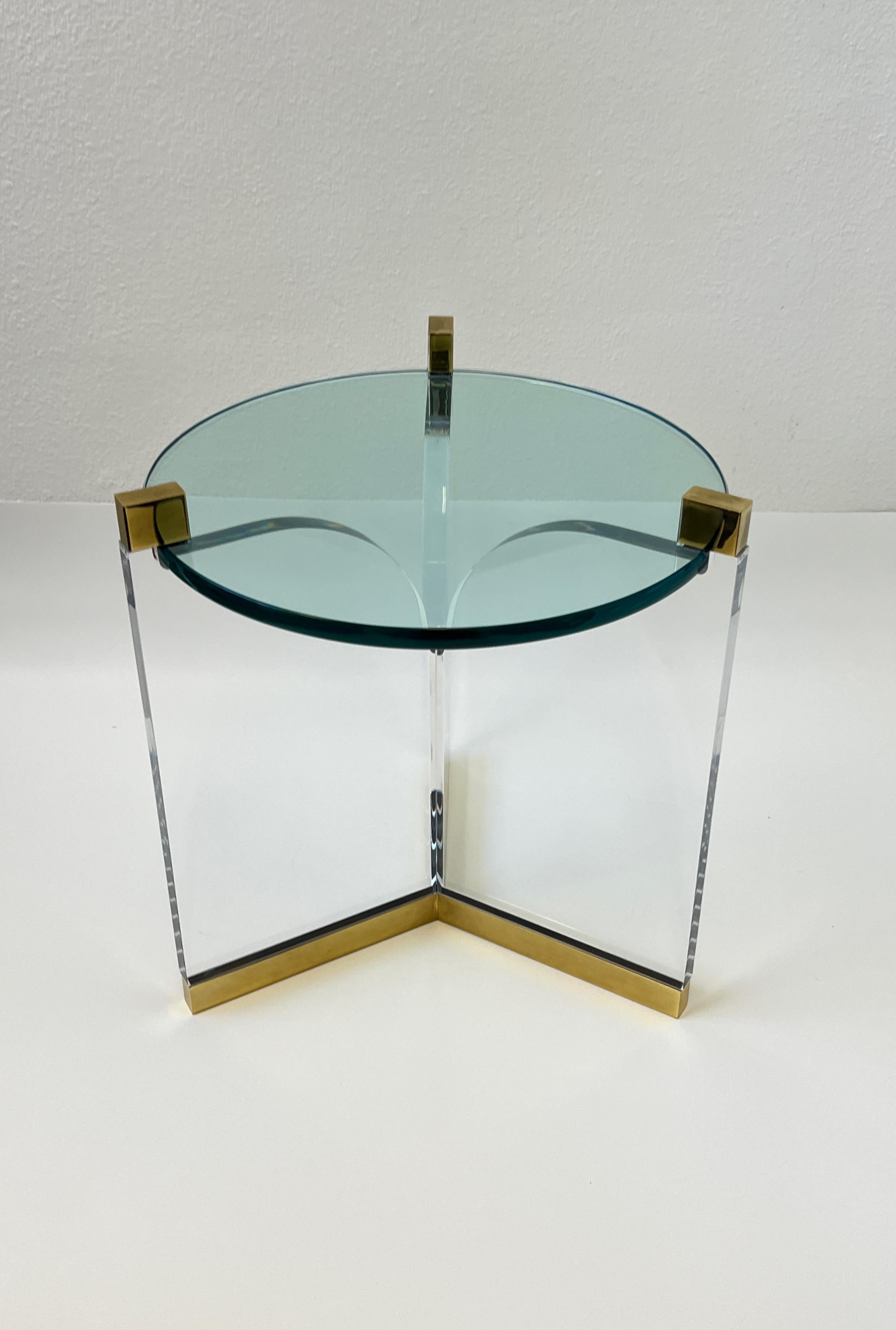 Glamorous 1970’s clear lucite and polish brass with a 3/4” thick glass top side table. 
Designed by renowned American designer Charles Hollis Jones. 
In beautiful vintage condition with minor wear consistent with age. 
Measurements: 21” wide, 21”