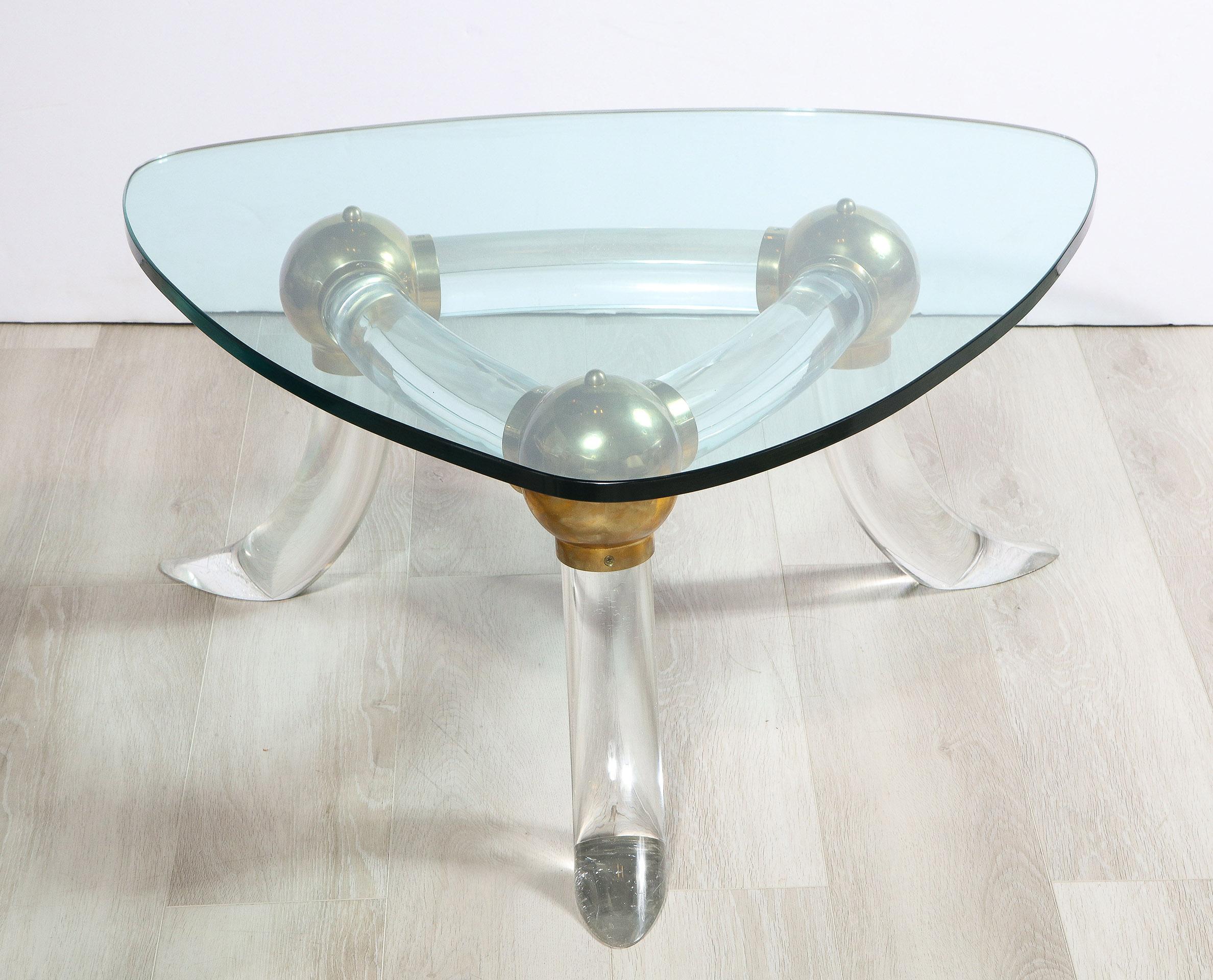 The triangular form lucite and brass base supporting a glass top of similar form.