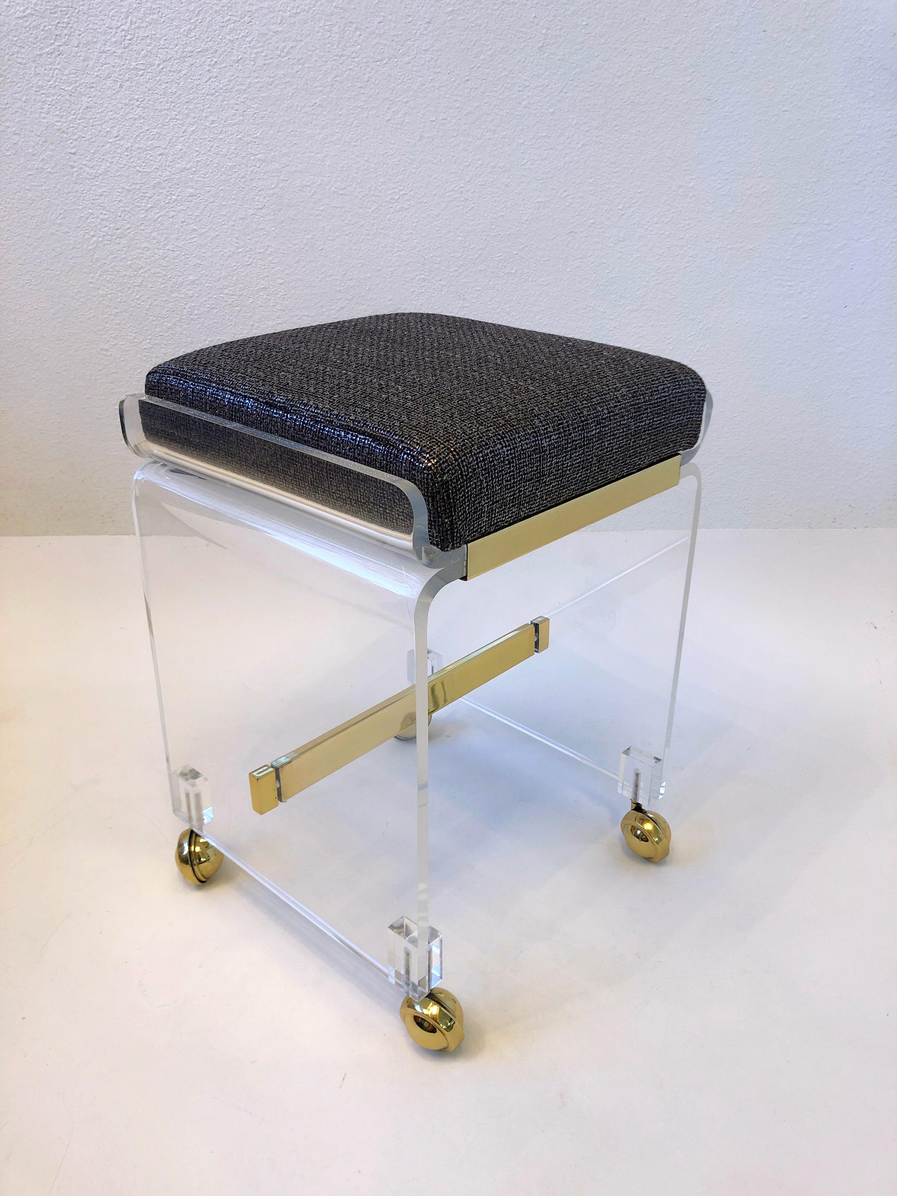 1970’s Clear lucite and brass waterfall vanity stool by American renowned designer Charles Hollis Jones. 
The lucite has been newly professionally polished, the polished brass replated and the seat is newly upholstered in a dark brown with a silver