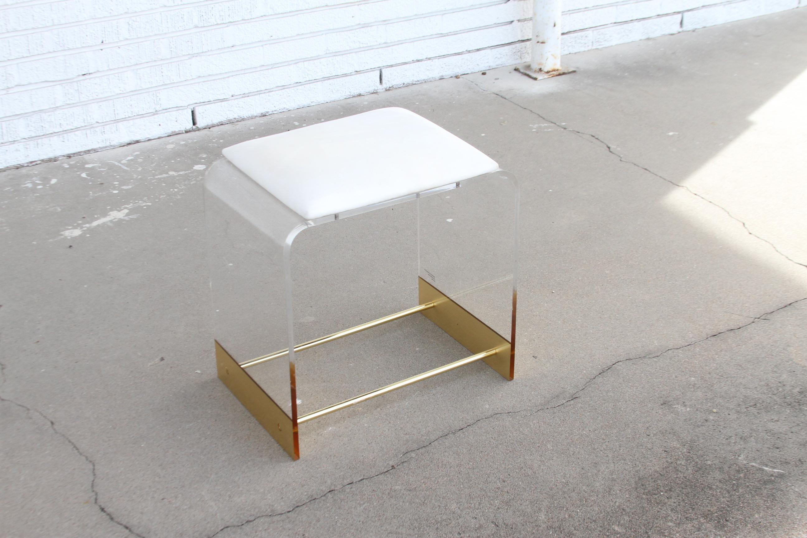 Ce tabouret de vanité est construit en laiton et lucite avec un siège en vinyle blanc. Les deux barres en laiton confèrent au tabouret une stabilité accrue. Le design de la cascade est de style Art déco. La lucite a une épaisseur d'un mètre.

Une