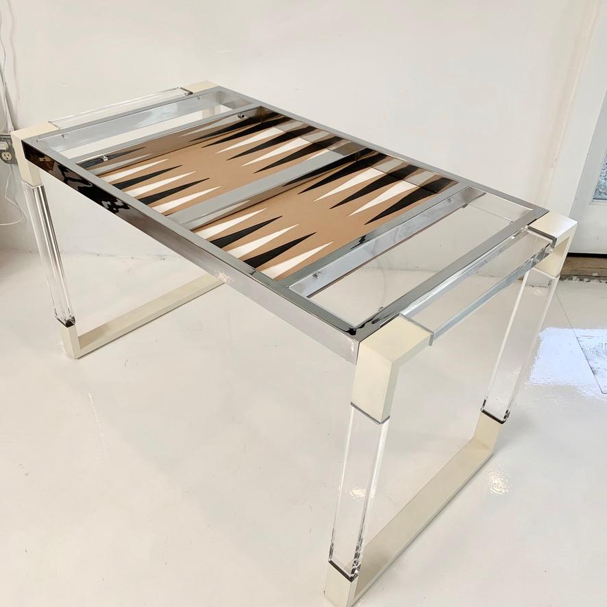 Vintage Lucite and chrome backgammon table. Rectangular frame with metal corners and Lucite crossbars. Chrome table top with Lucite covers. Felt game area, with black and white leather triangles. Removable cover. Some wear throughout. Overall good