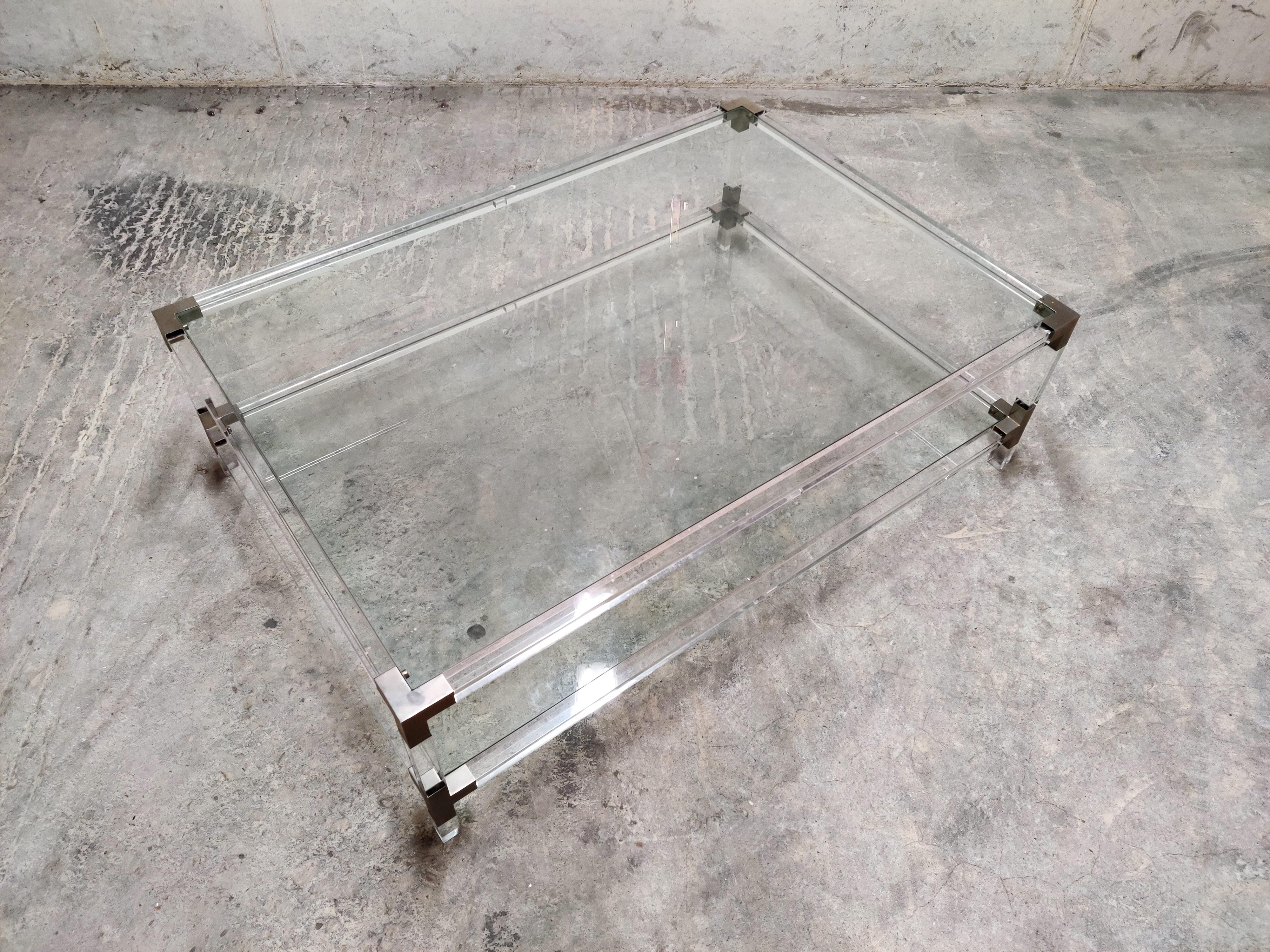 Rectangular coffee table with a Lucite frame, chrome/metal corners and clear glass plates.

Good condition.

Very modern looking and decorative table that can be combined with lots of interior styles.

Patina on the brass.

Good
