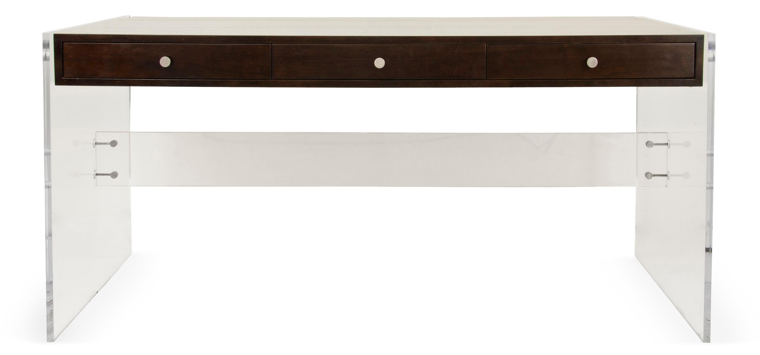 A highly engineered modernist desk made from a walnut (or oak, mahogany, or rosewood veneer) case “floating” on a Lucite base, which is affixed by custom-designed hardware. Custom sizes and finishes available.