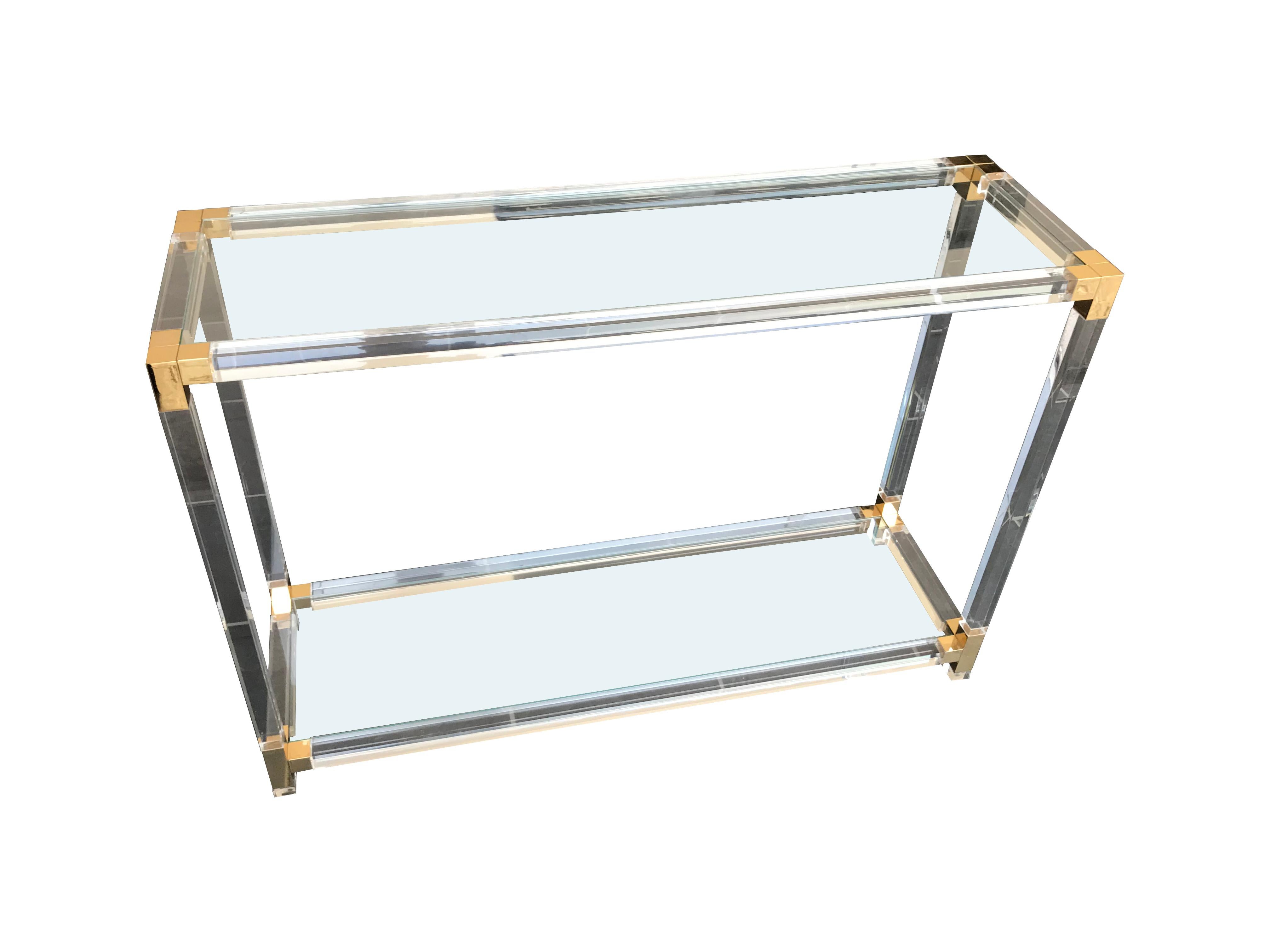 A Lucite and gilt console table with two glass shelves.