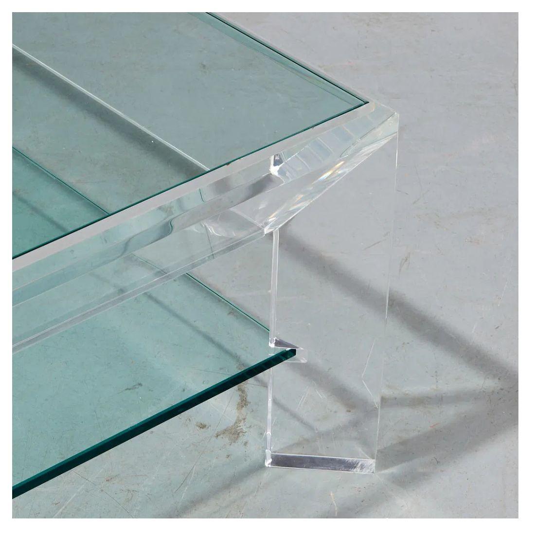 Questo tavolino vintage in lucite e vetro, progettato nello stile di Charles Hollis Jones, presenta un design elegante e minimalista. La struttura angolare in lucite sostiene un piano in vetro fluttuante con un ripiano inferiore in vetro, offrendo