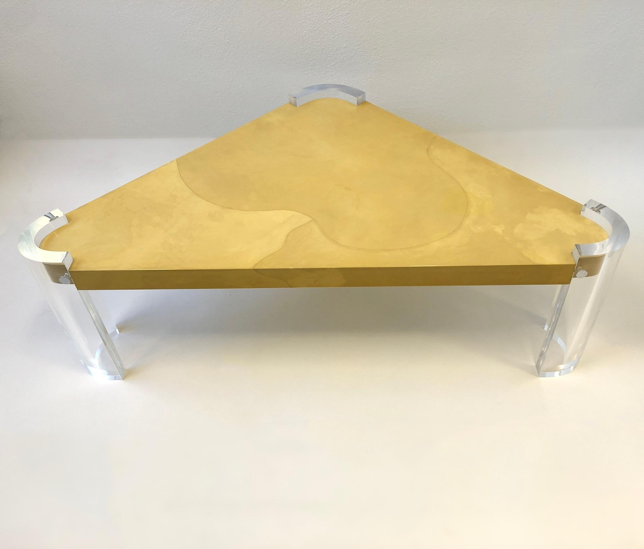 Spectacular 1980’s clear lucite and lacquered goatskin, triangular shaped cocktail table in the manner of Karl Springer.
In beautiful condition. Lucite leg have been newly professionally polished. 
Measurements: two sides are 42” wide, one side is