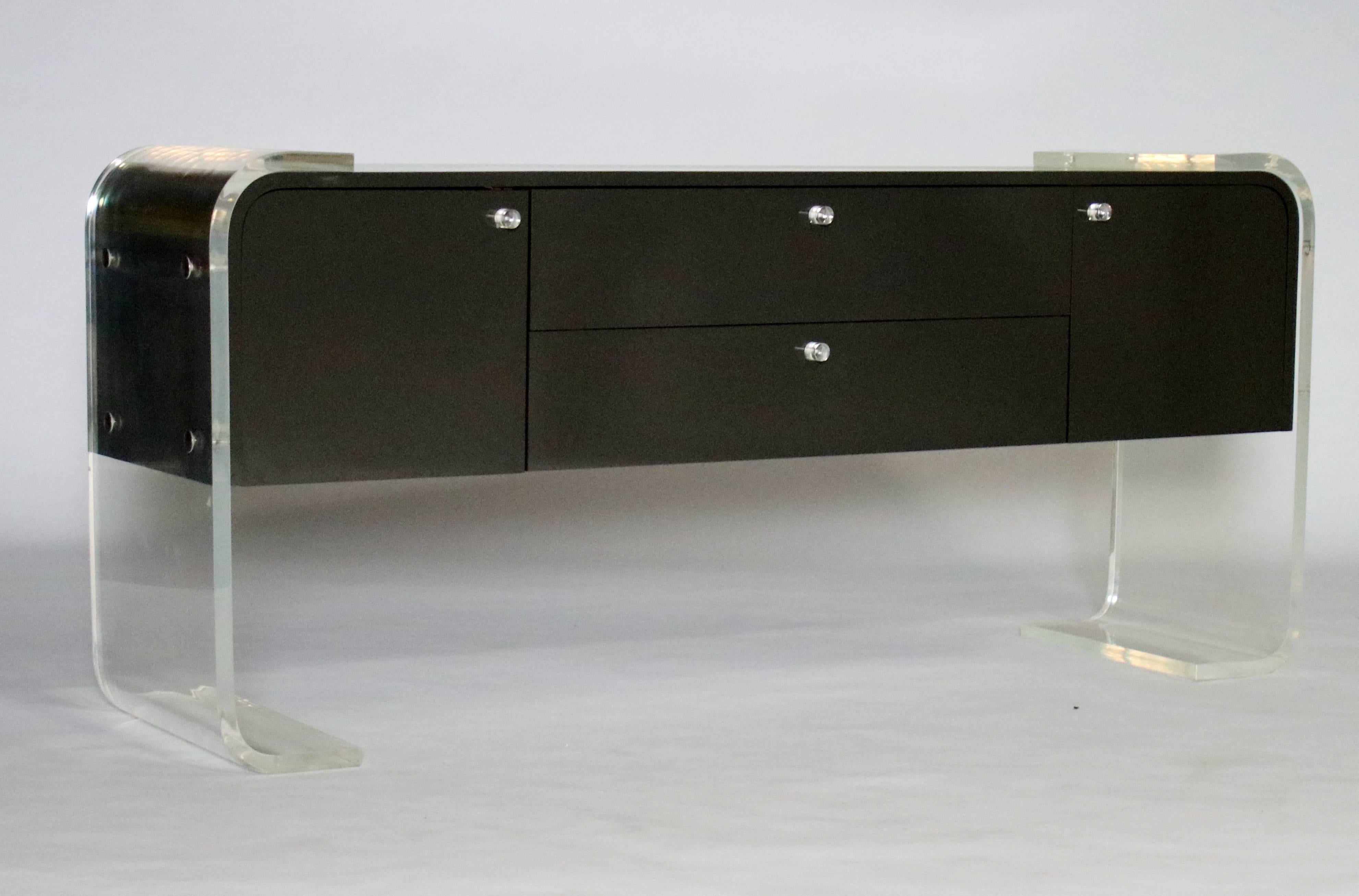 1970s lacquered charcoal gray wood buffet on a thick Lucite frame in the style of Pace or Milo Baughman. Features two cabinets and two pull-out drawers with wood interiors and original Lucite hardware. Both the cabinet and the Lucite in very good