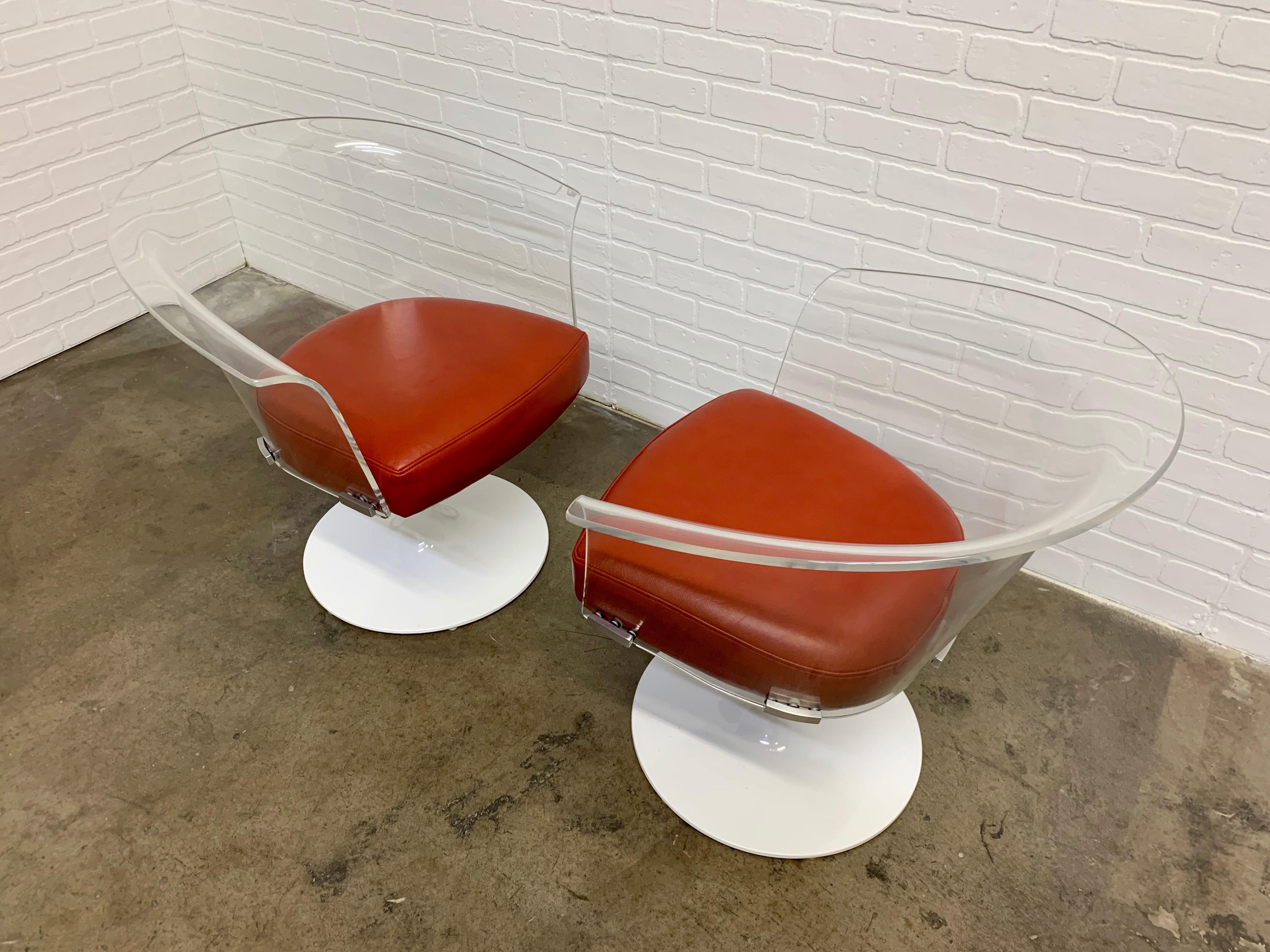 Paire de fauteuils pivotants vintage du milieu du siècle dernier en acrylique Space Age avec cuir orange sanguin et bases récemment revêtues de poudre.