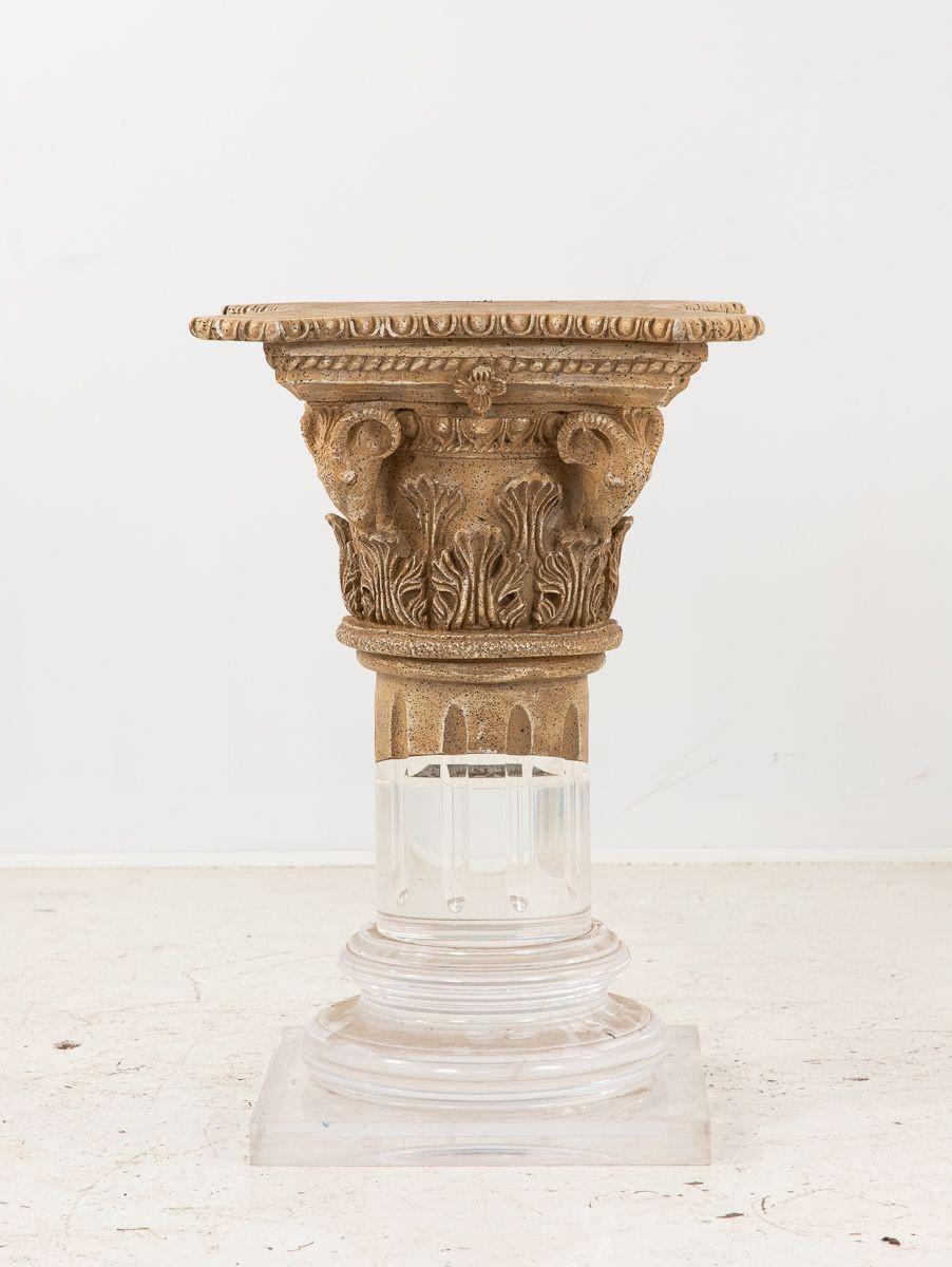 A late 20th-century pedestal column made of lucite and limestone. The base is made of clear lucite with some scuffing. The top half of the column is ornately and exquisitely carved limestone. The limestone features acanthus leaves, ram's heads, egg