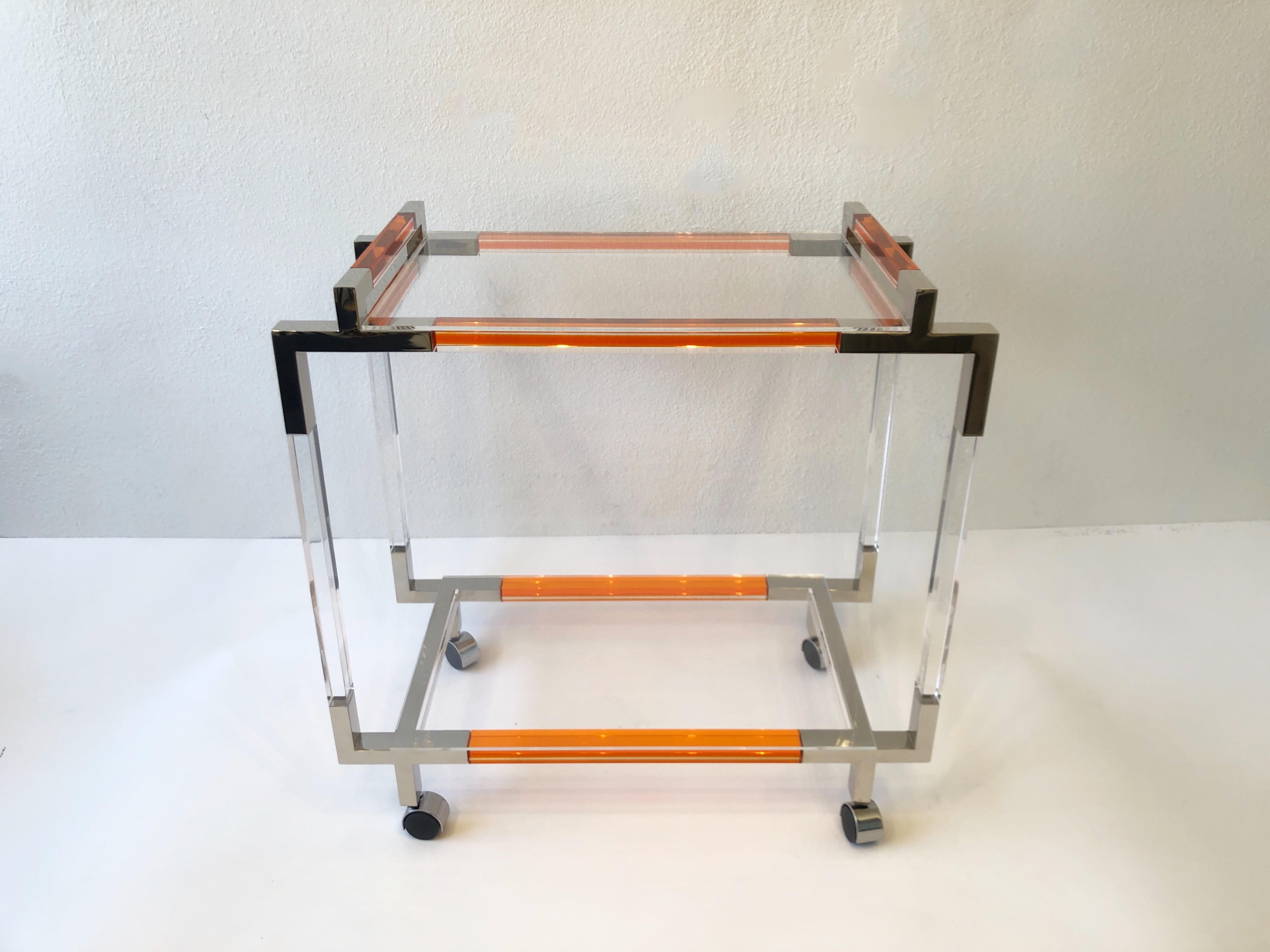 Polish nickel and orange acrylic two tier bar cart by American renowned designer Charles Hollis Jones. 
Measurements: 17” deep, 32” wide 31.75” high.