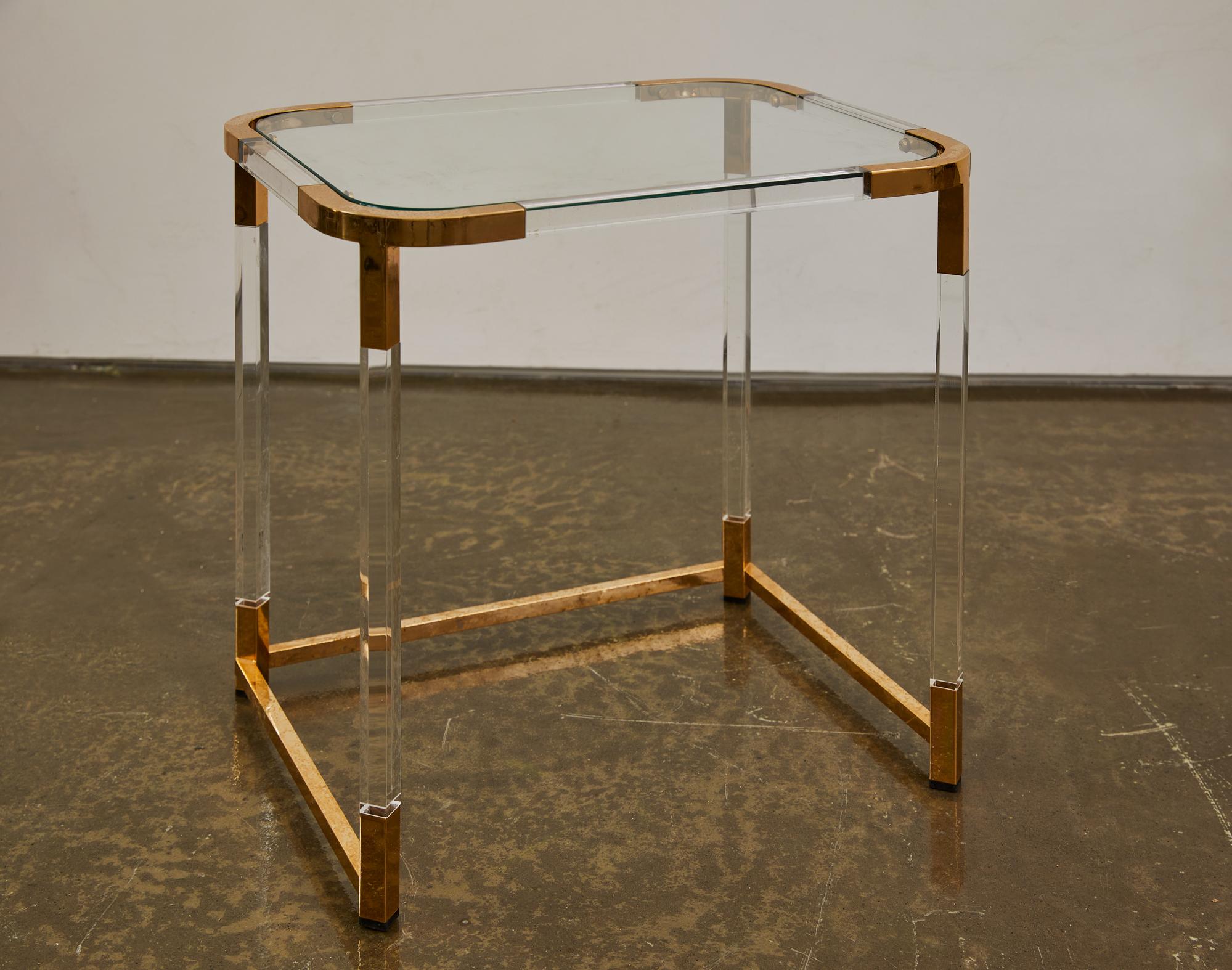 This Modernist Lucite and polished brass side table, crafted in the 1930s, reflects the sleek design principles of Charles Hollis Jones. The lightweight Lucite surface is supported by a polished brass frame with clean lines and a refined geometric