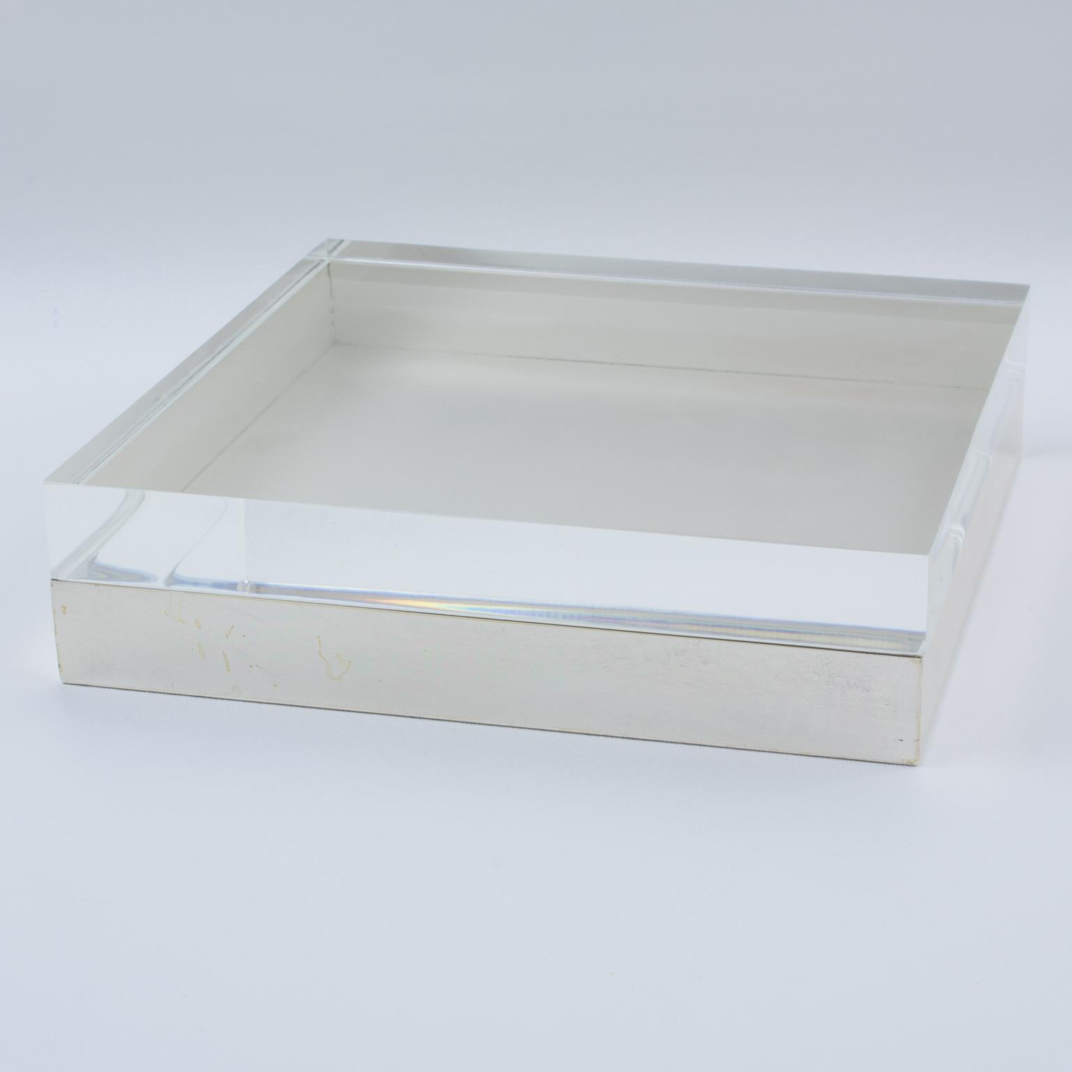 The massive geometric shape boasts a silver plate metal base and a thick crystal clear Lucite lid. There is no visible maker's mark.
The box is in good condition, with minor wear on the metal, but It does not significantly affect the overall