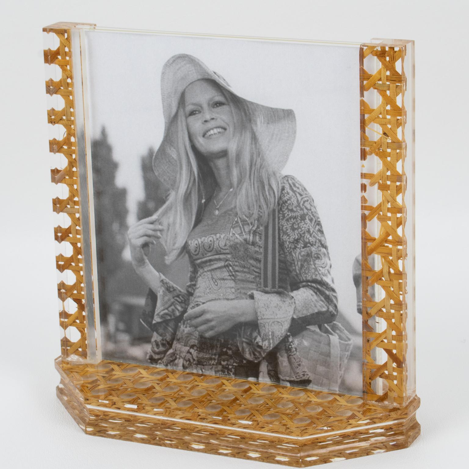 Este precioso marco modernista se fabricó en Italia en la década de 1970. La pieza tiene una base hexagonal de losa gruesa de Lucite con dos soportes altos. El marco de la foto está hecho de Lucite transparente con auténtico trabajo de ratán, mimbre