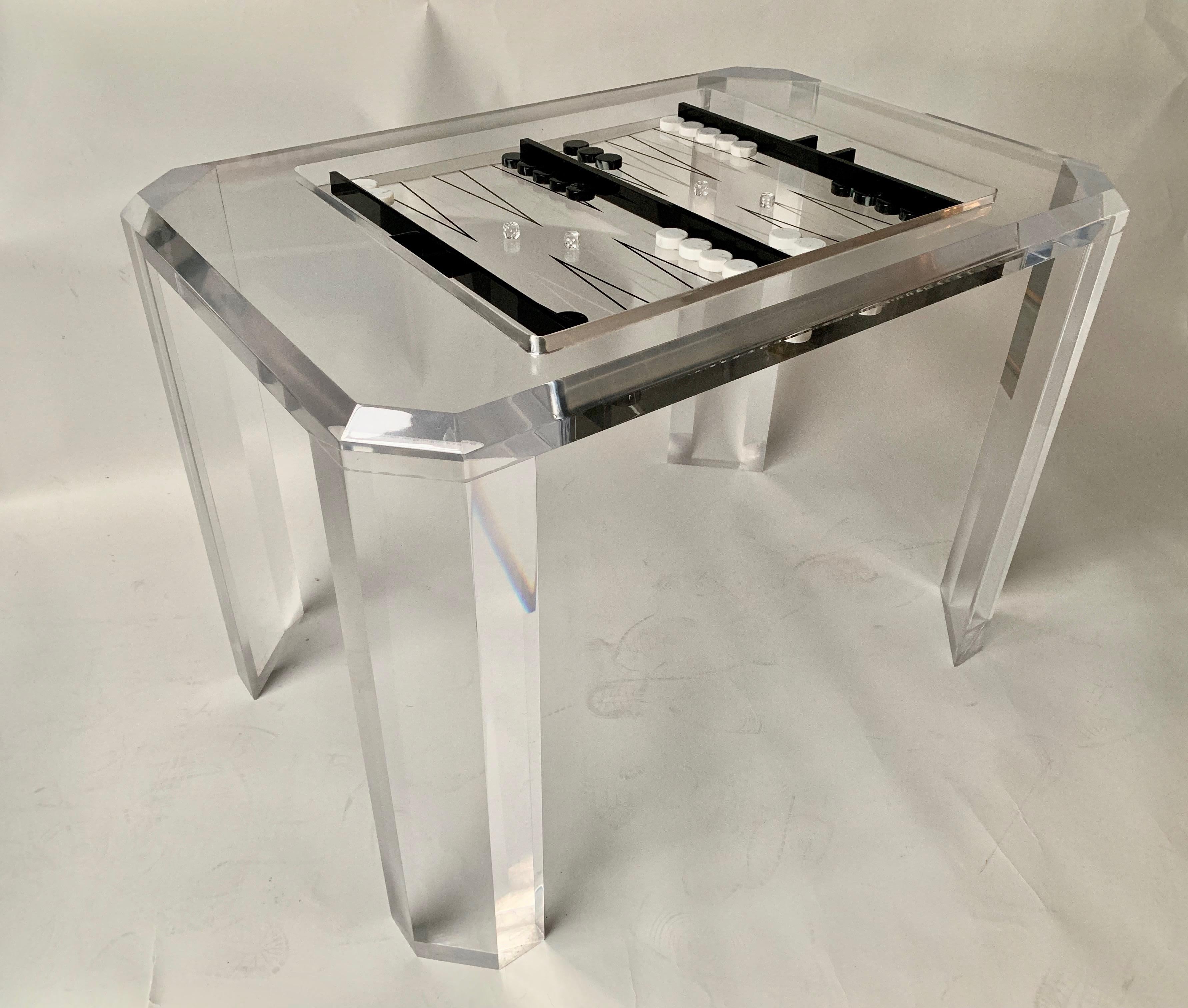 Vintage Lucite backgammon table with faceted legs and top. Great lines. Inset backgammon board made of Lucite as well. Bakelite chips in black and white along with acrylic dice included. Thick glass game board cover with two finger holes for