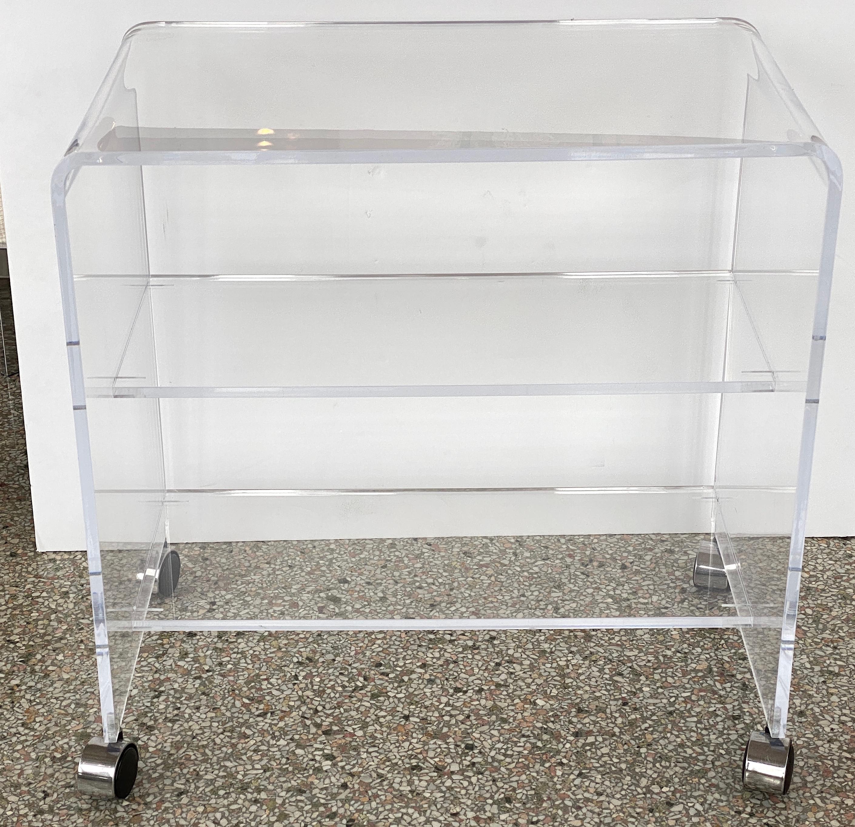 This styish waterfall-form lucite bar cart is very much in the style of pieces created by Holllis Jones.

Note: Overall measurements are 26