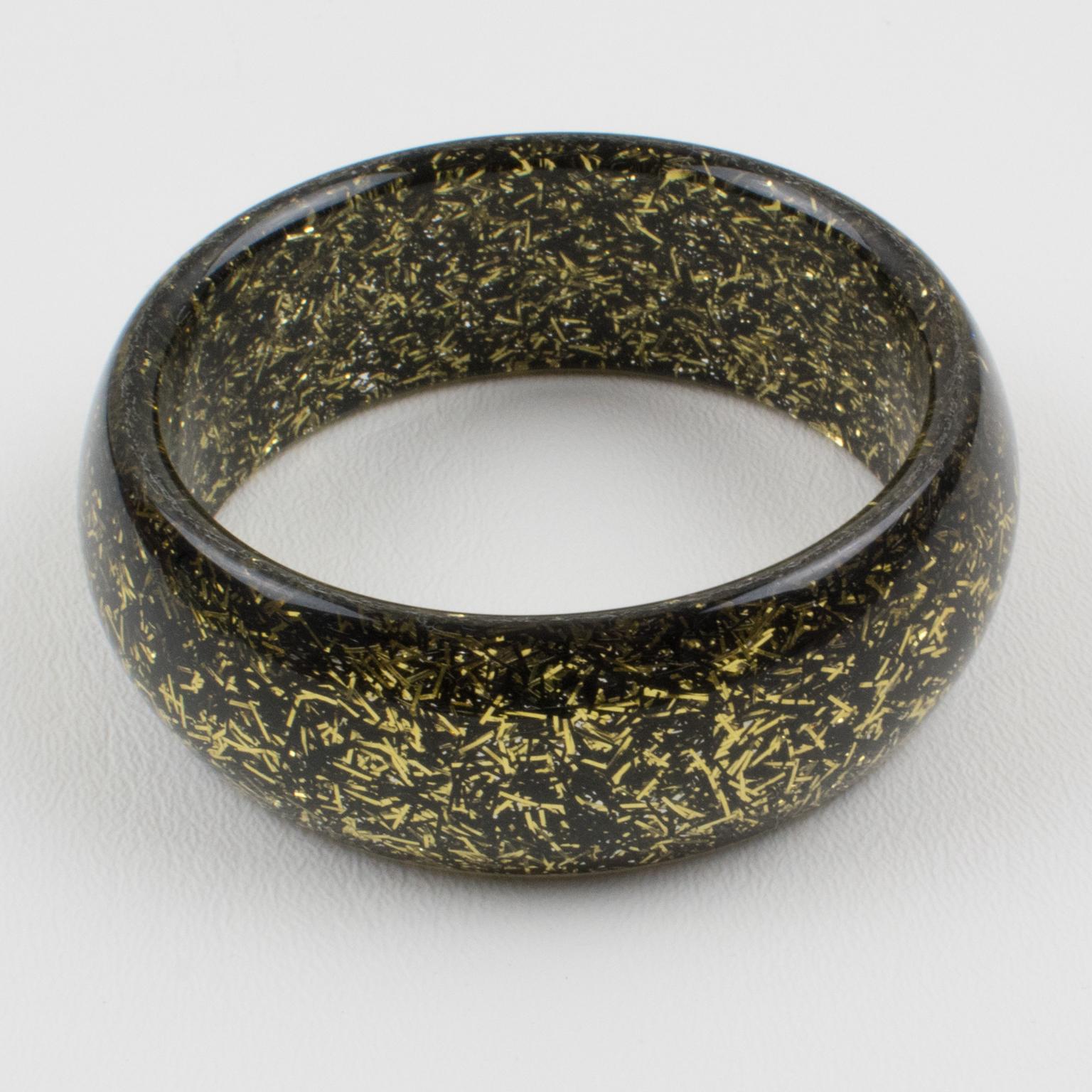 Lovely Lucite bracelet bangle. The bangle has a domed shape and is comprised of clear Lucite injected with metallic thread inclusions in black and gold colors. The metallic threads sparkle as those of Christmas tinsels. There is no visible maker's