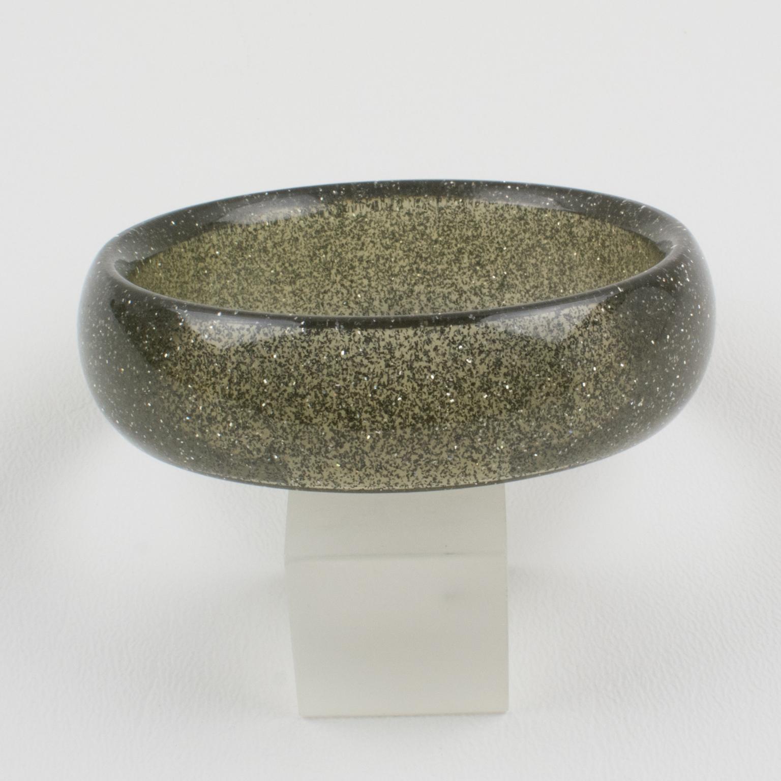 Charming Lucite bracelet bangle. The bangle has a domed shape and is comprised of transparent smoked gray Lucite, which is injected with metallic confetti inclusions in silver color. The metallic confetti glitter is like that of Christmas