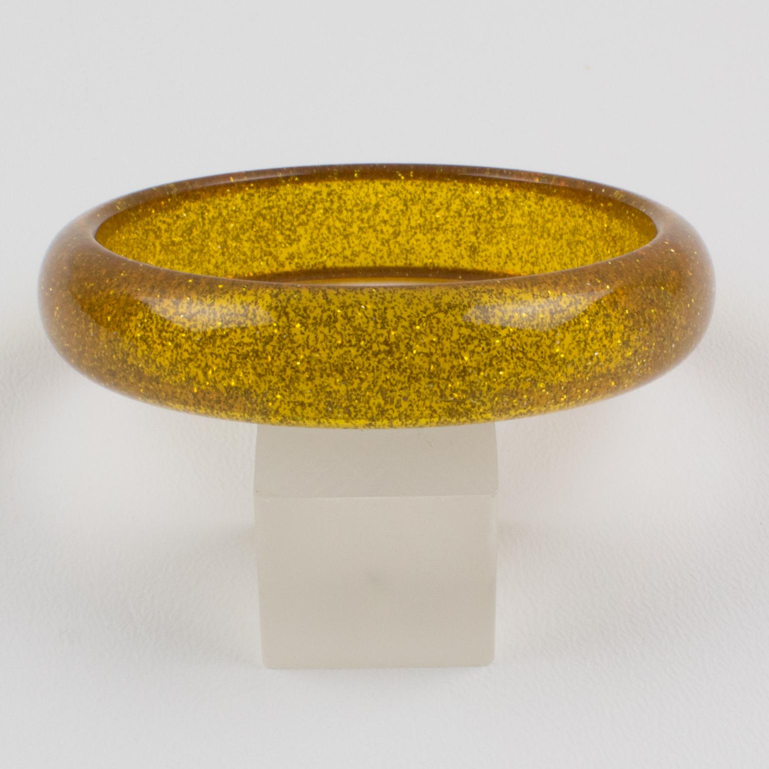 Charming Lucite bracelet bangle. The bangle has a domed shape and is comprised of transparent yellow marigold Lucite which is injected with metallic confetti inclusions in gold color. The metallic confetti glitter is like those of Christmas