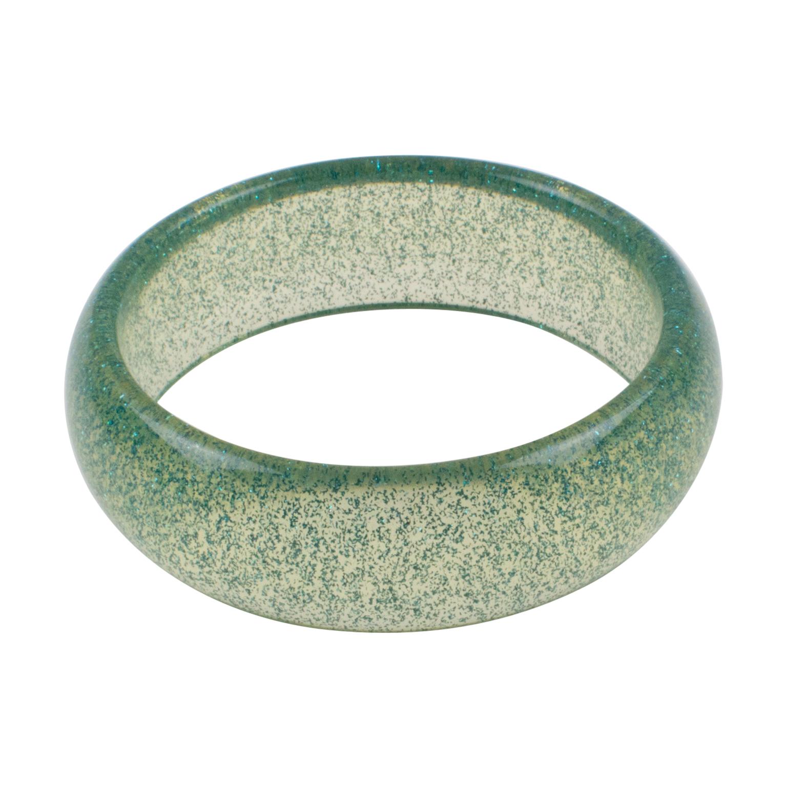 Charming Lucite bracelet bangle. The bangle has a domed shape and is made of clear Lucite and an injection of metallic confetti inclusions in turquoise color. The metallic confetti glitter is like those of Christmas decorations. There is no visible