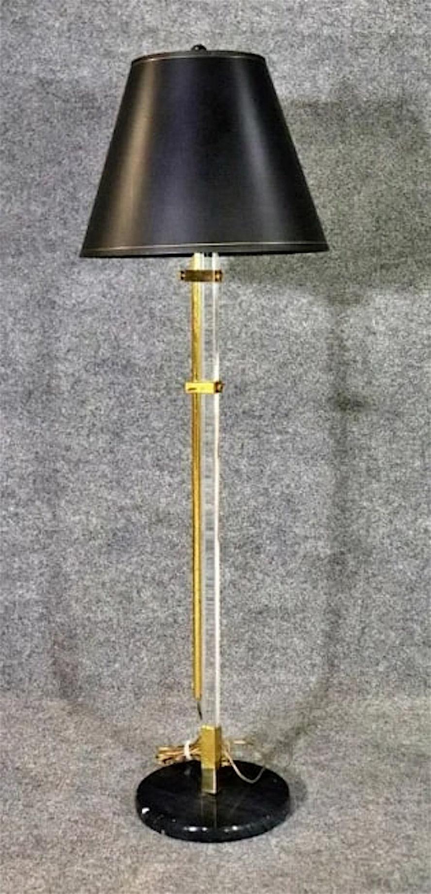 Adjustable floor lamp with polished brass and clear lucite, set on a black marble base, with black and gold shade.
Base: 10
