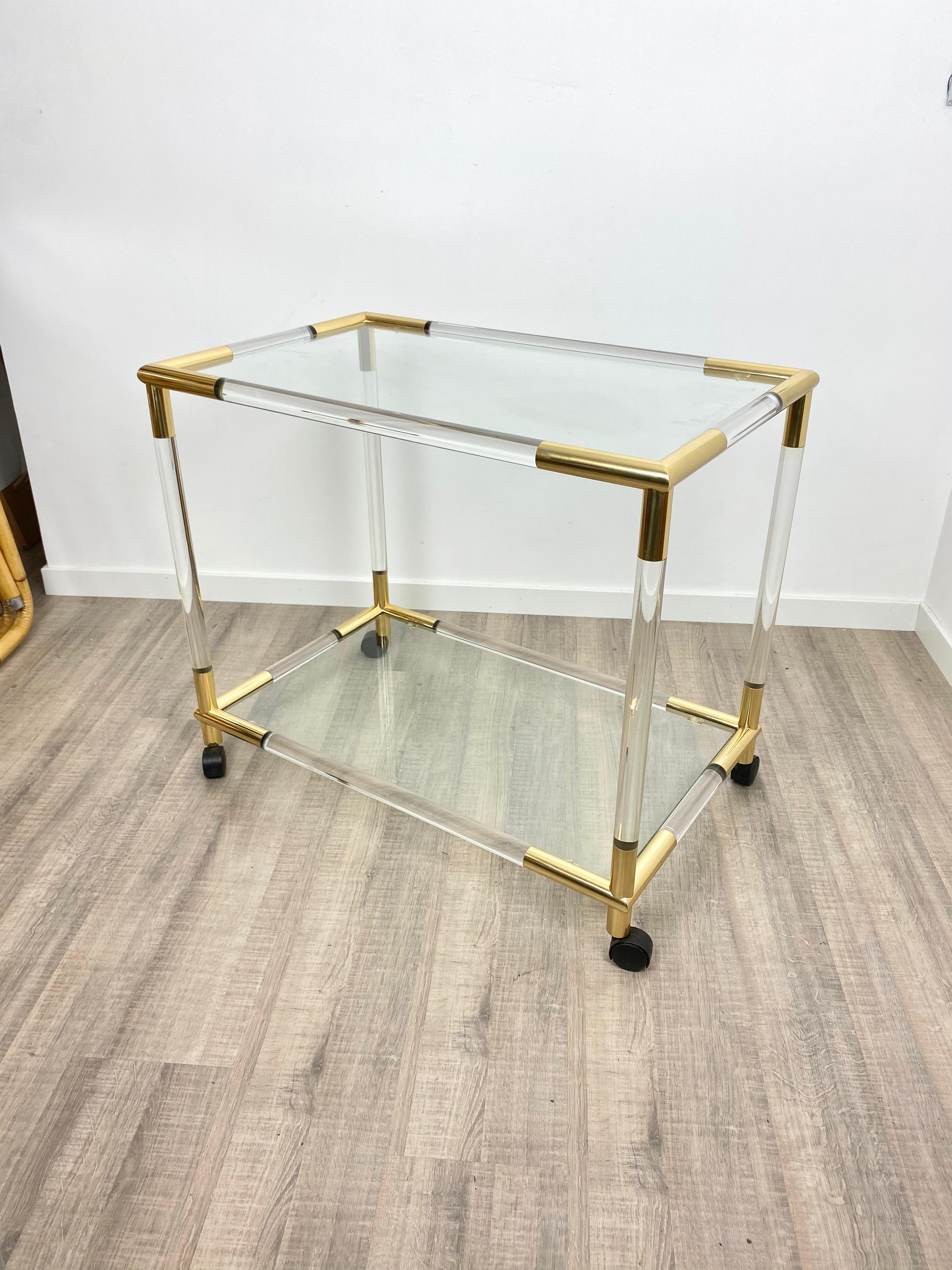 Bar serving cart trolley in Lucite structure and brass details with two glass shelves. Original from Italy, 1960s.