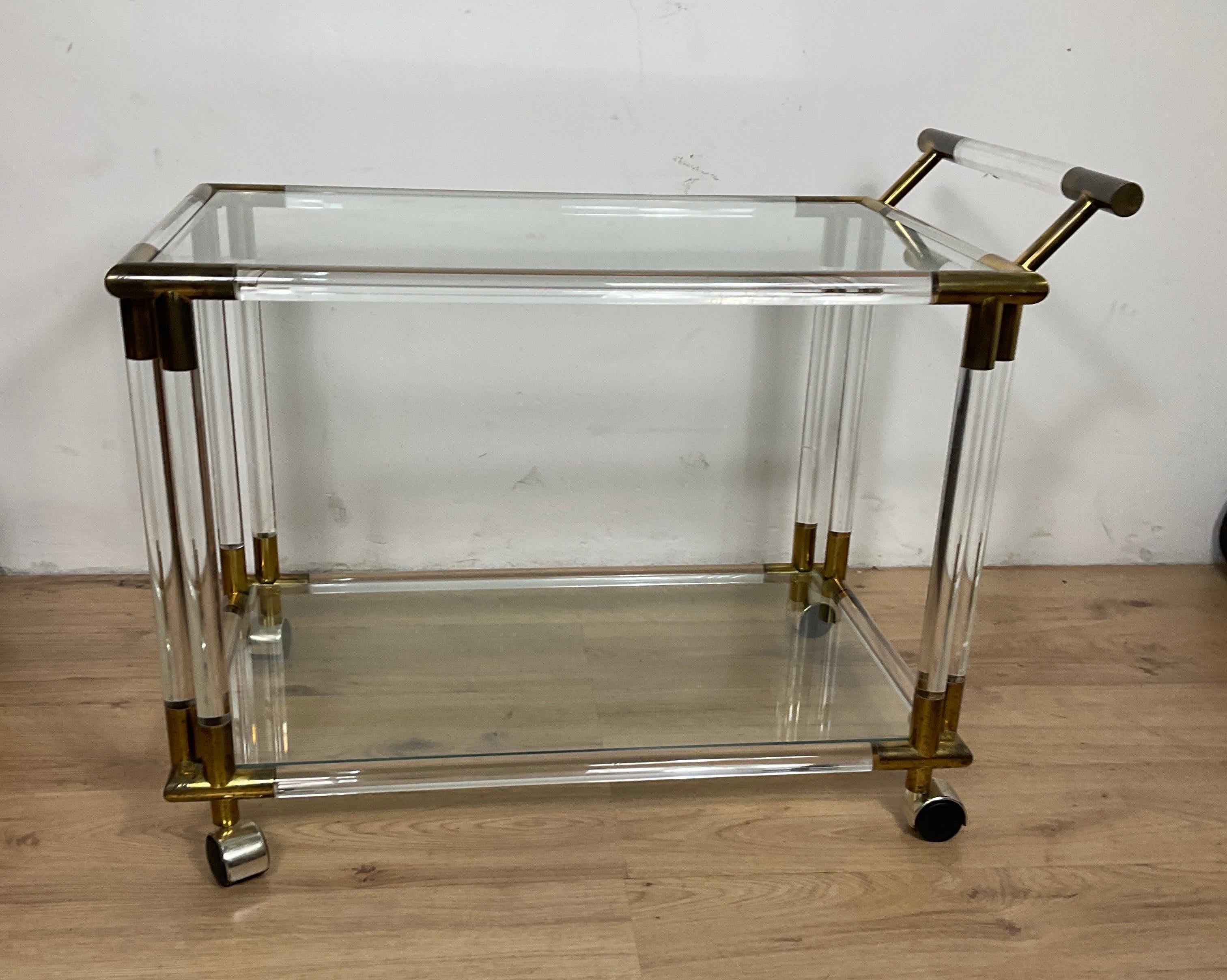 A stunning lucite and glass designer bar/tea cart with brass accents on quality casters