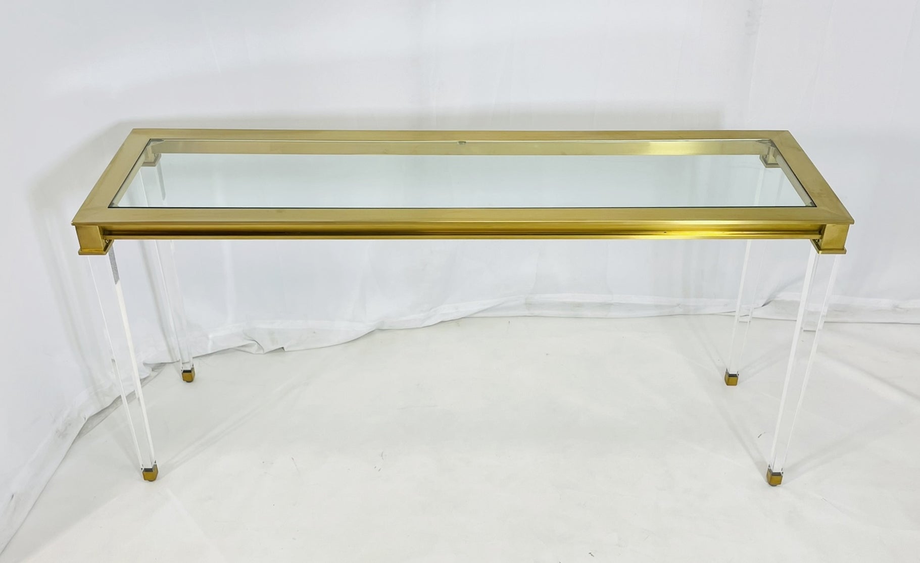 Introducing our Lucite & Brass Console Table With Glass Top after Charles Hollis Jones, a stunning addition to any modern space. Crafted with high-quality lucite and brass materials, this console table exudes elegance and sophistication. The sleek