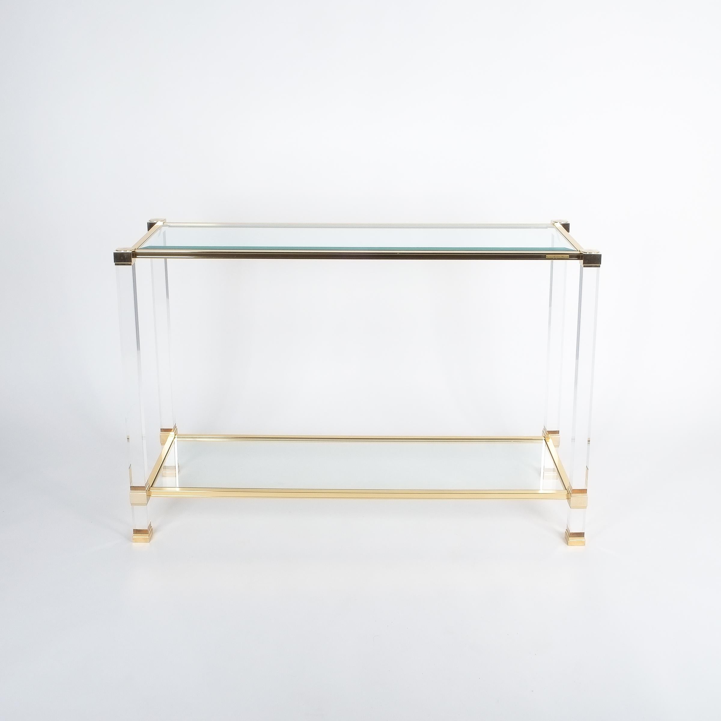 Classical console table by Pierre Vandel/Paris, France. Consisting of Lucite pillars and brassed metal beams. Beveled top glass and normal shelf glass both with no chips. The table is in good to excellent condition. Labelled Pierre Vandel.