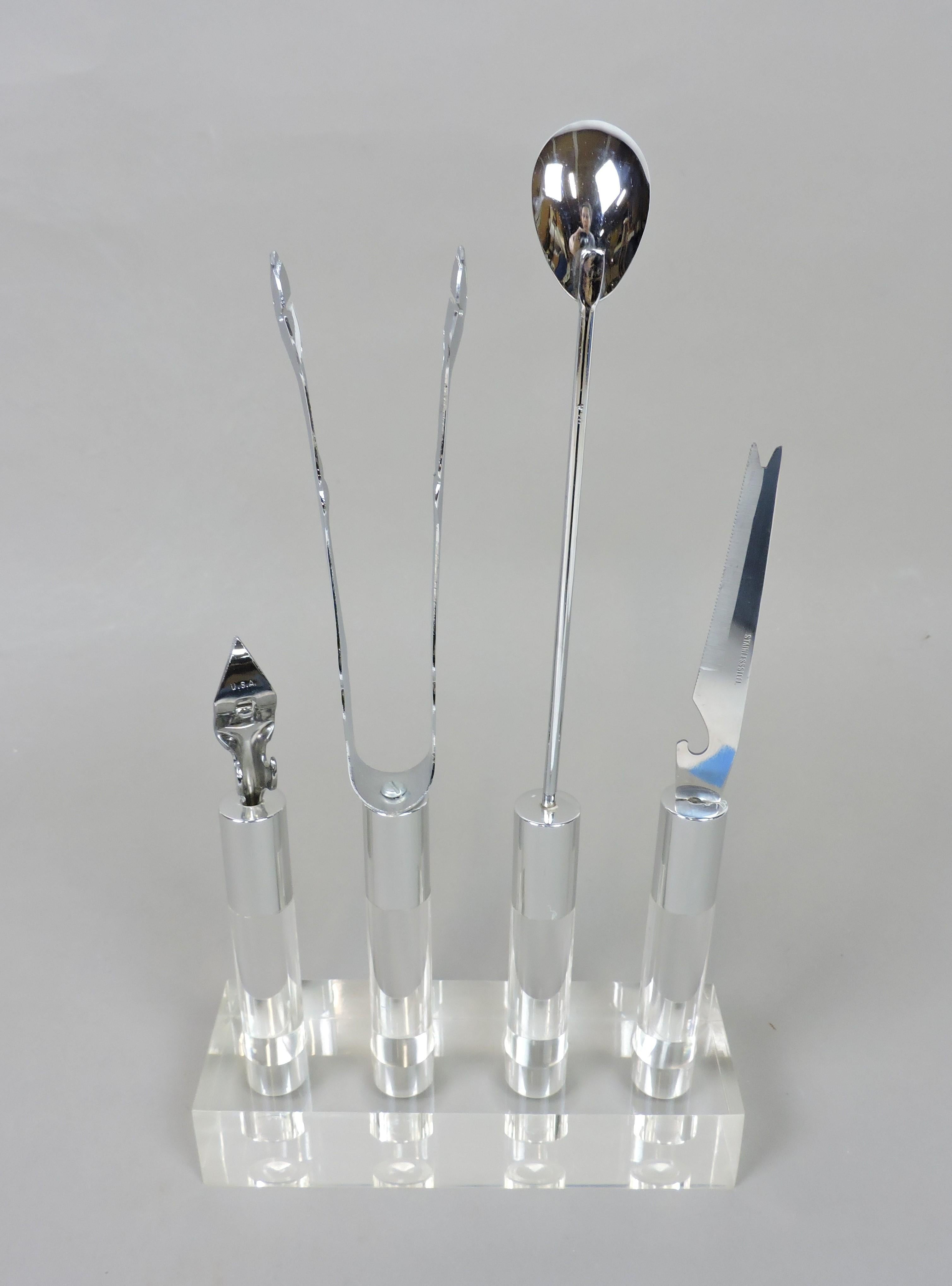 Beautiful 5 piece barware set made of Lucite, chrome and stainless steel. This stylish set consists of a 13 1/4 inch long stirring spoon, a 12 inch pair of tongs, a 10 inch condiment knife, and a 7 1/2 inch bottle/can opener. All utensils have a