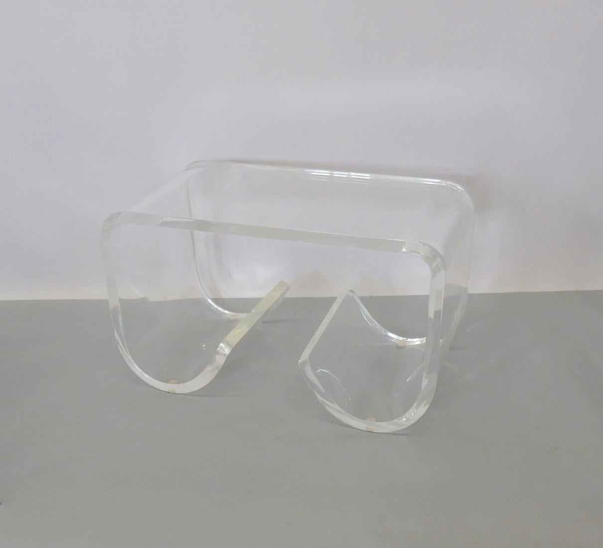 Acrylic or Lucite cocktail table or bench. Sides roll down to the floor and curl into center for possible magazine storage. Would adapt easily as a bench with or without your added cushion.