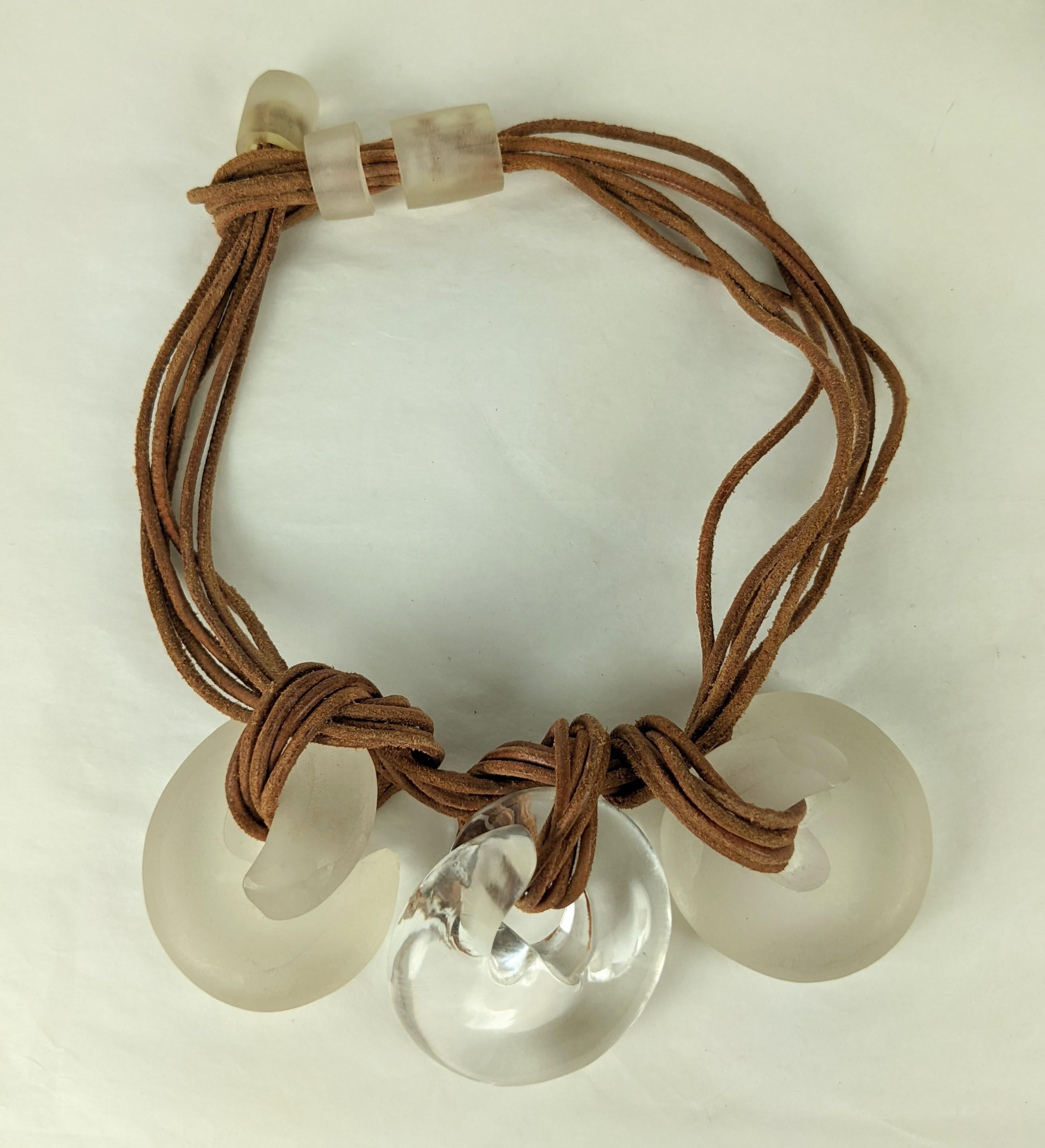 Striking Lucite Coil and Rawhide Pendant Necklace from the 1980's in the style of Cara Croninger. 3 hand carved lucite swirls are knotted onto rawhide with frosted lucite hilts and clasp. 2 of the swirls have matte frosted finish and the central one