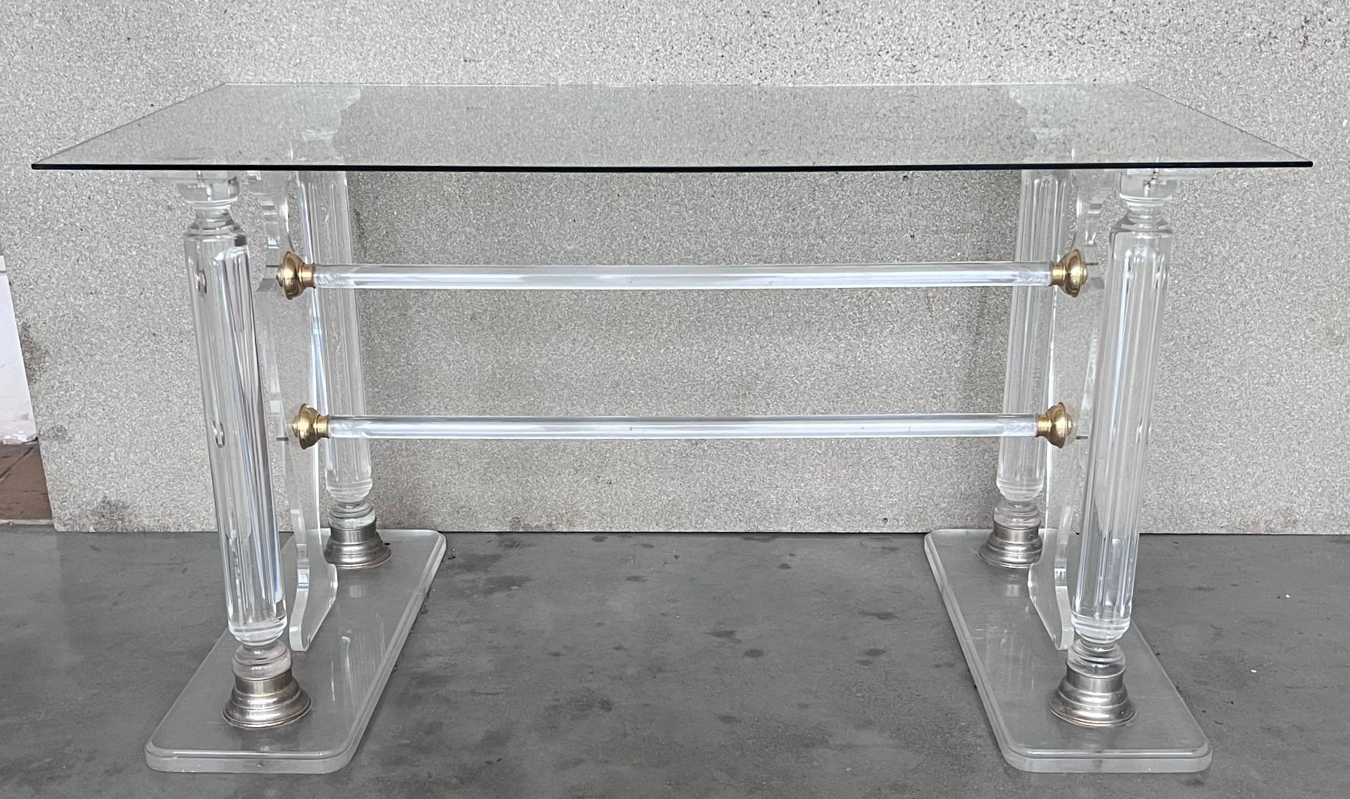 An impressively Lucite console in the manner of Karl Springer with glass top. 
It has two lyre pedestal flanked by two columns in each side. Both pedestal are joined by two lucite stretchers.