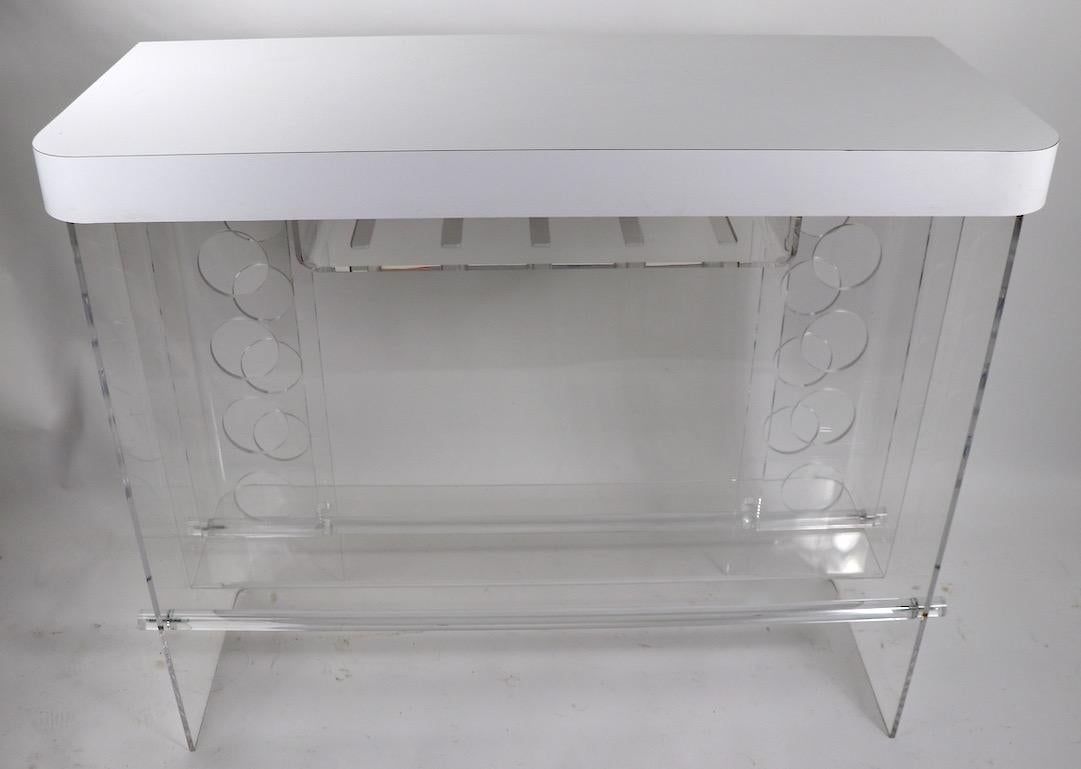 Classic 1970s Lucite counter bar with white formica top. The Lucite base has a series of holes designed to hold your bottles, and a slatted shelf for storing stemware, the top is white formica, top shows minor cosmetic specifically very light